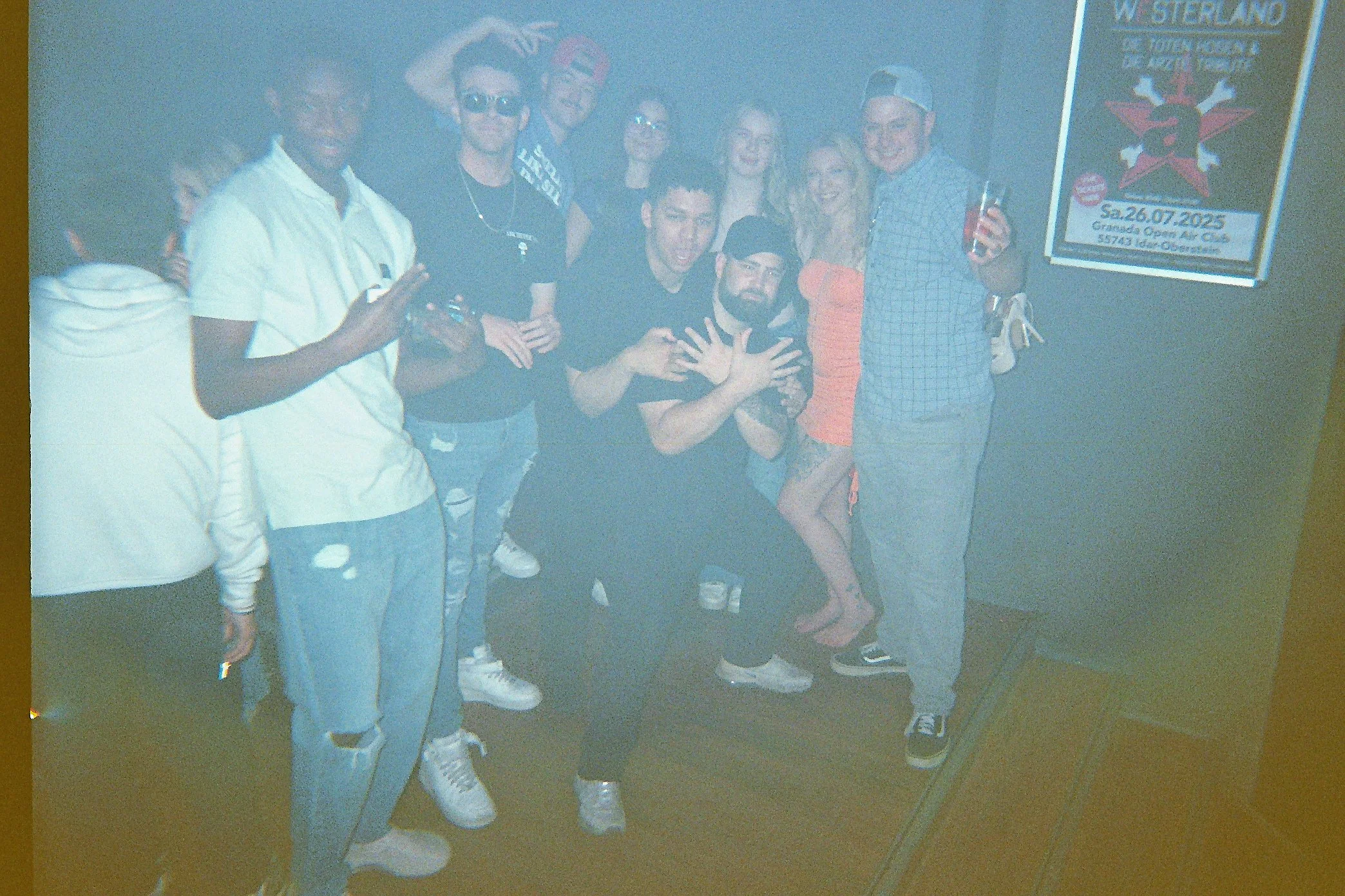 Gruppe junger Menschen feiern zusammen, einige tragen Sonnenbrillen und haben Getränke in der Hand, bei einer Party in einer Bar oder einem Club.