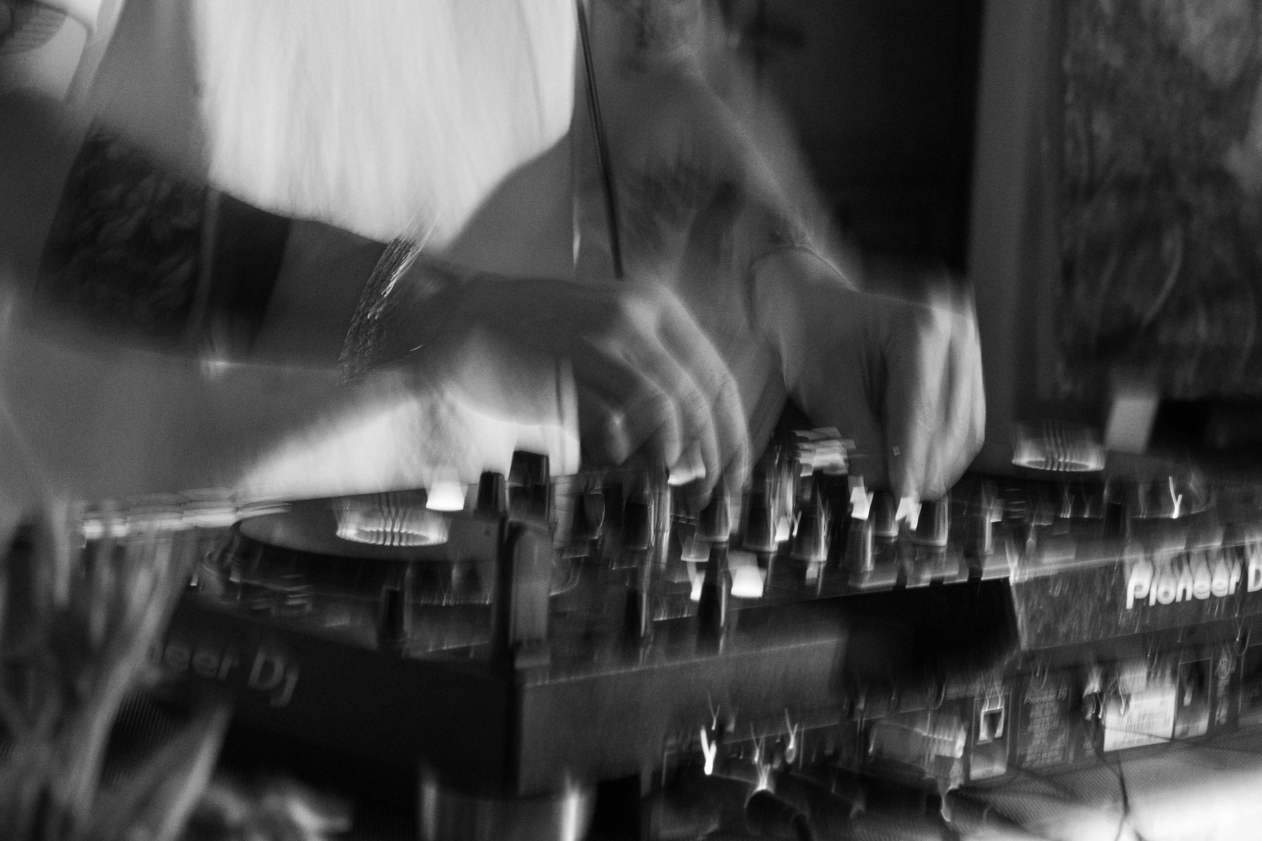 Le mani di un DJ che manovrano un mixer in bianco e nero.