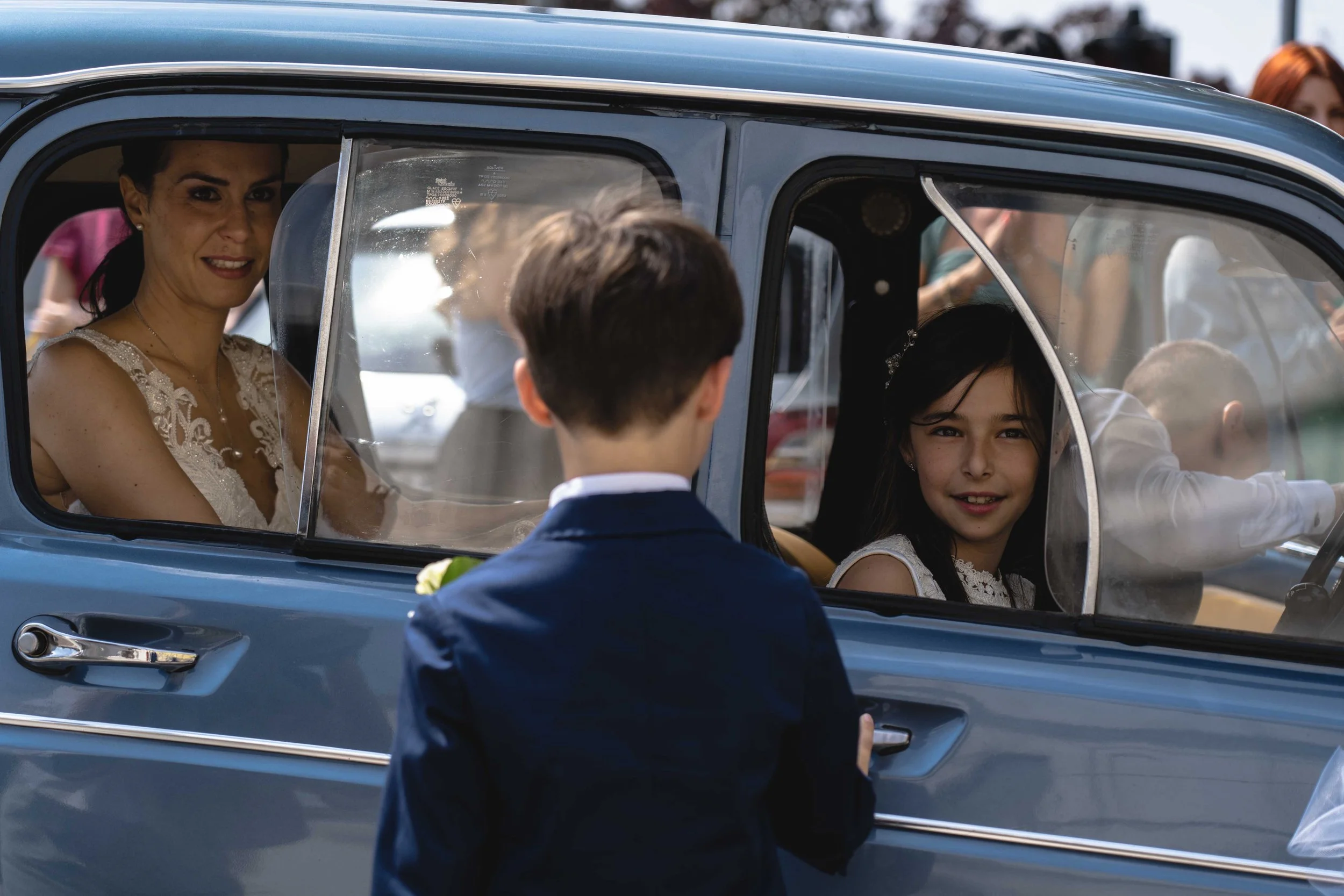 Bambini e adulti in un'auto d'epoca durante un'occasione speciale, come un matrimonio.