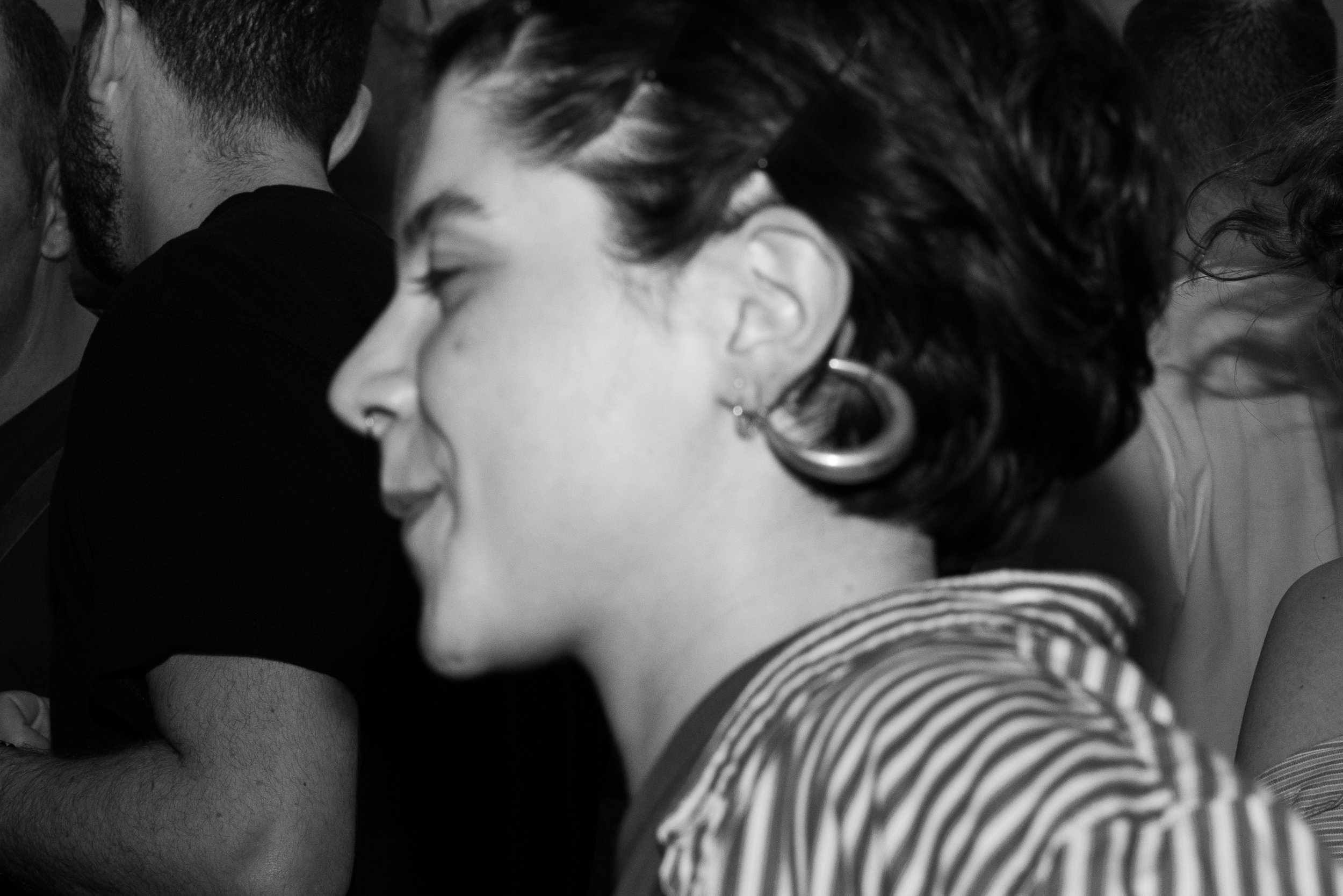 Ragazza con orecchini a cerchio, capelli corti e ondulati, sorridente, mentre la sua faccia è rivolta di lato, in un'ambientazione in bianco e nero.