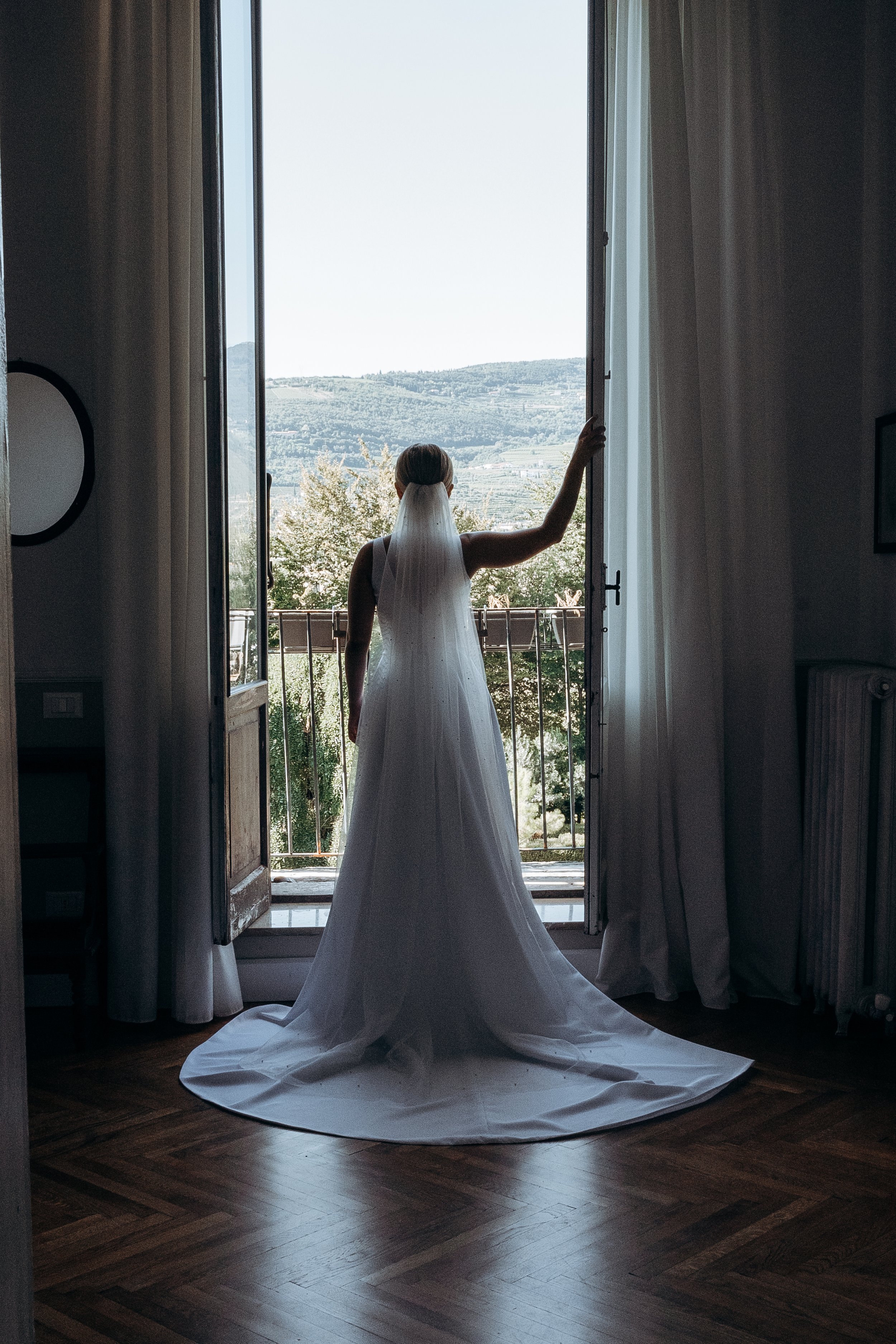 Sposa con abito bianco che guarda fuori dalla finestra