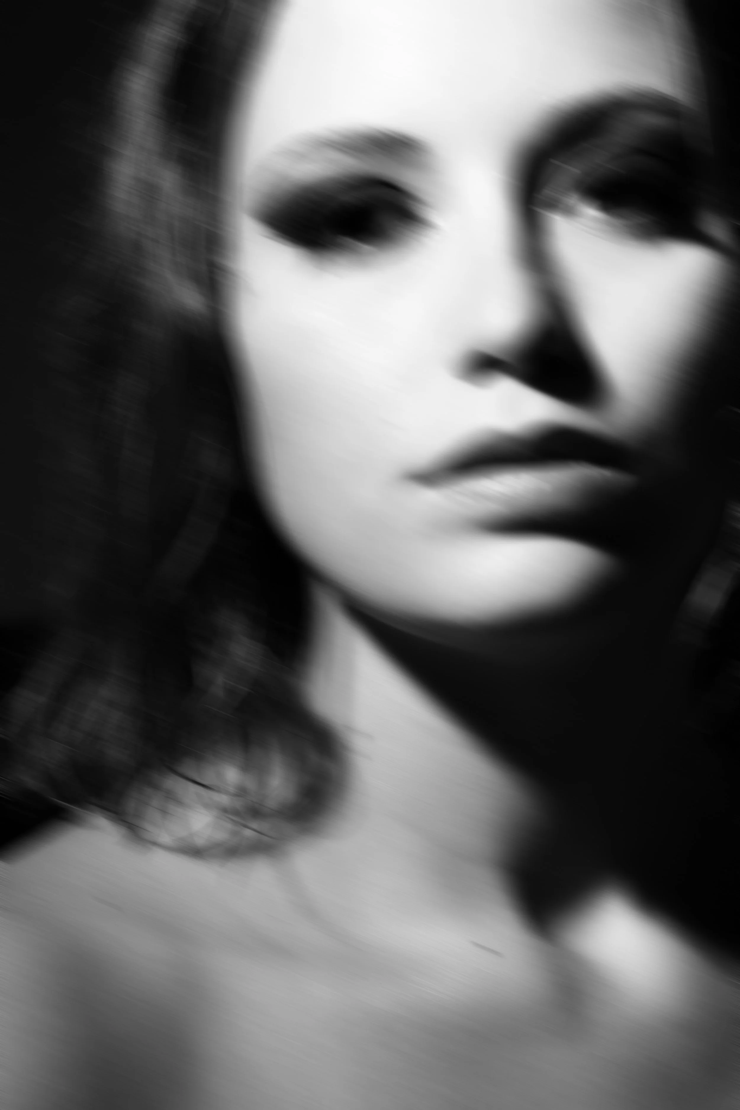 Ritratto sfocato di una donna con espressione seria, in bianco e nero.