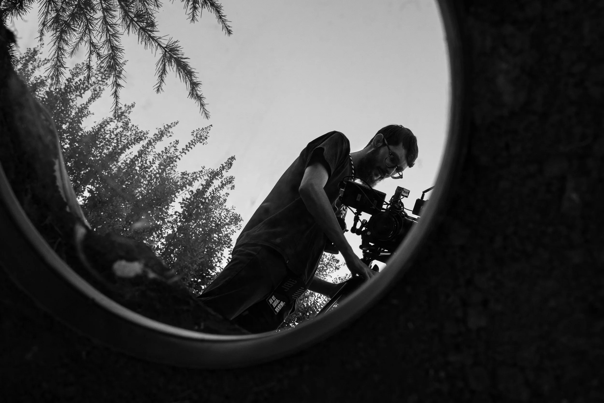 Persona che lavora con una videocamera, visibile attraverso un foro nel terreno o su una superficie.