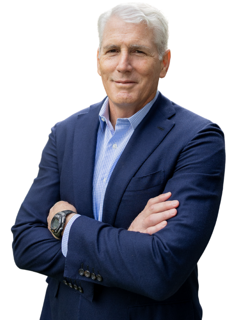 A man with white hair wearing a blue blazer and light blue checkered shirt, crossing his arms and smiling.