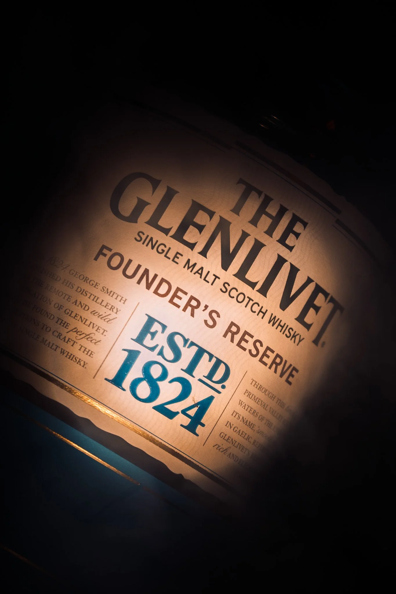 A bottle of The Glenlivet single malt Scotch whisky with label details visible, including the establishment year 1824.