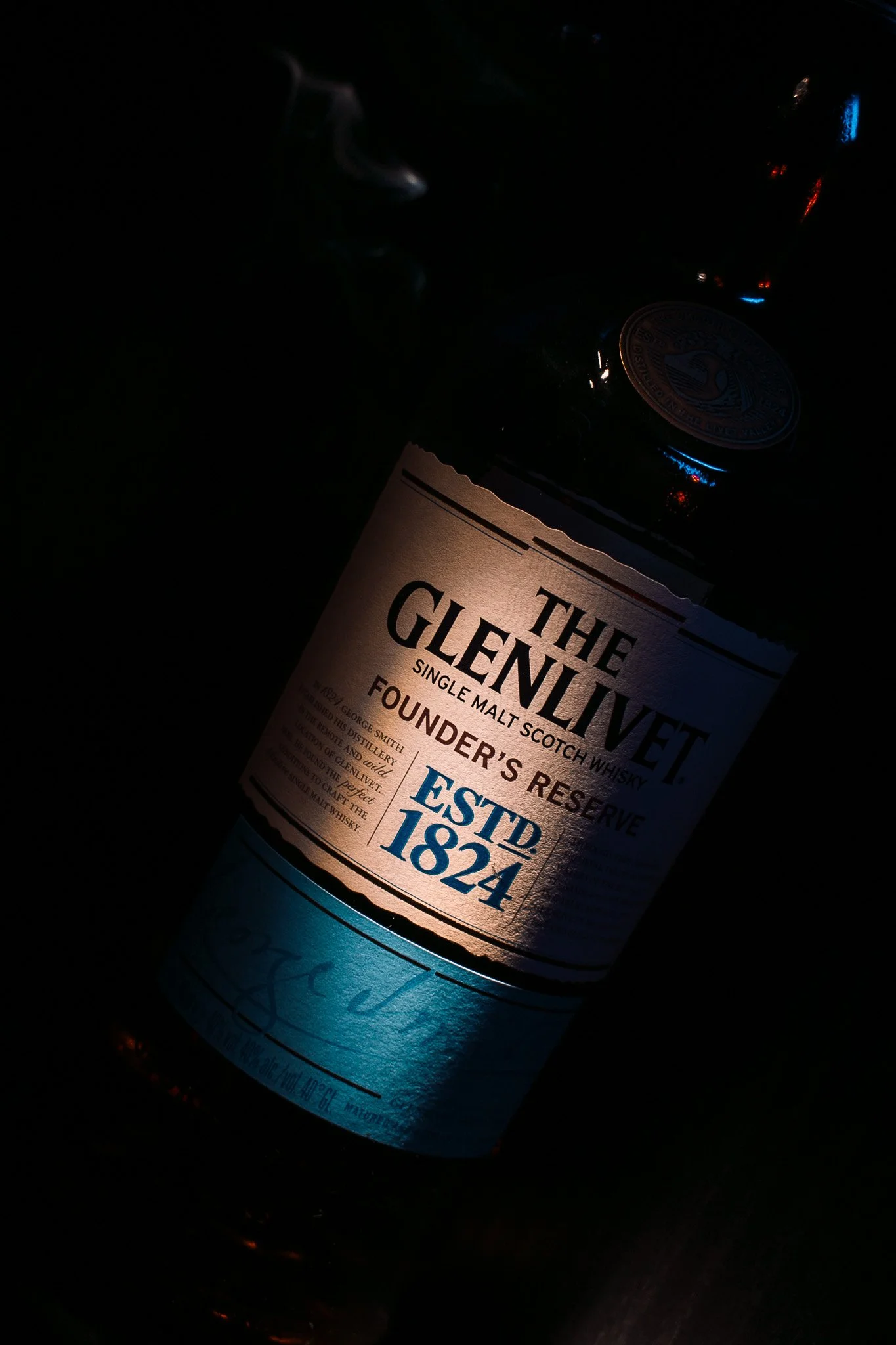 Close-up of a bottle of Glenlivet single malt Scotch whisky in dark lighting.