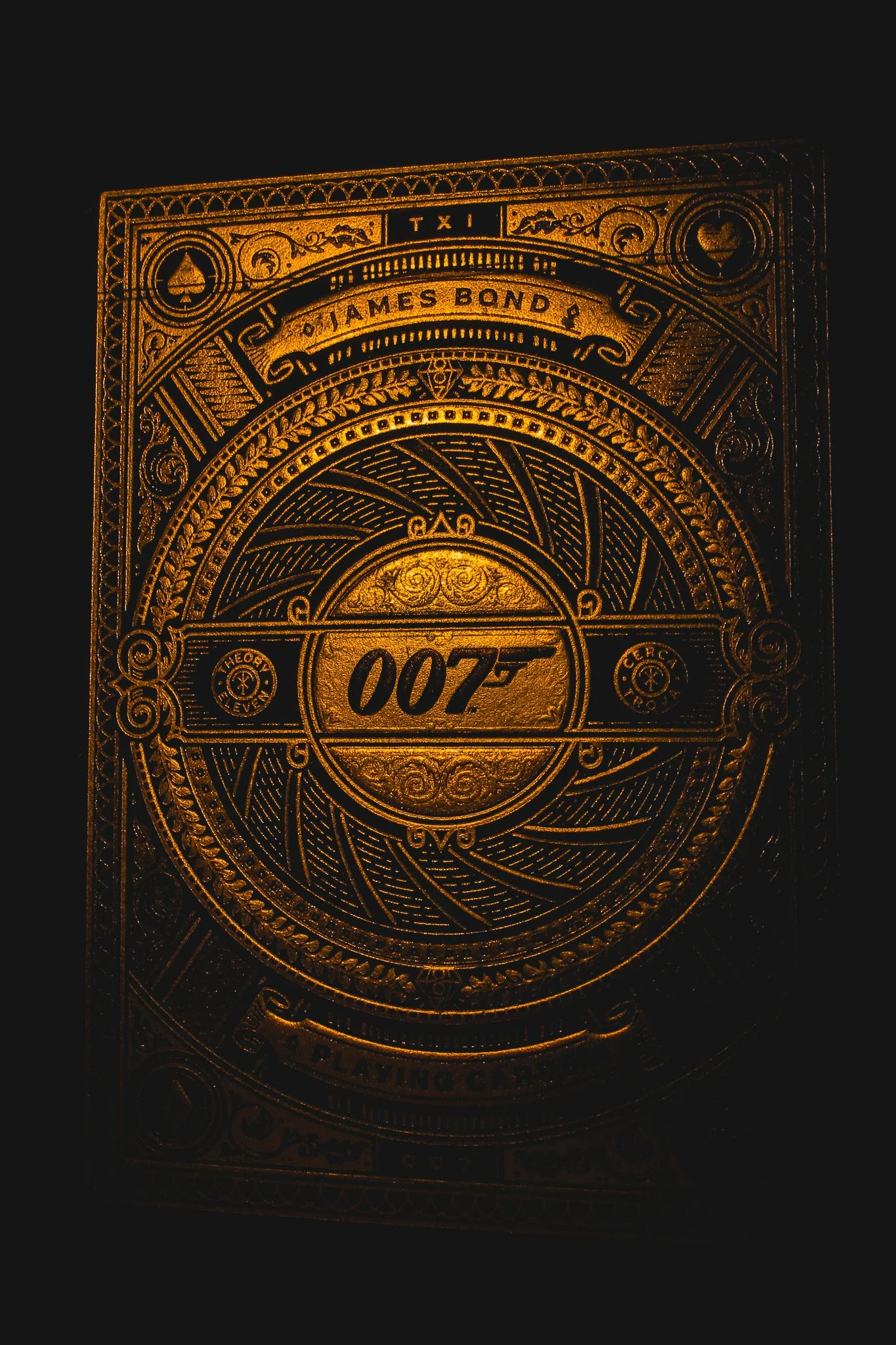 The back of a gold-colored playing card with intricate designs and the number 007 in the center.