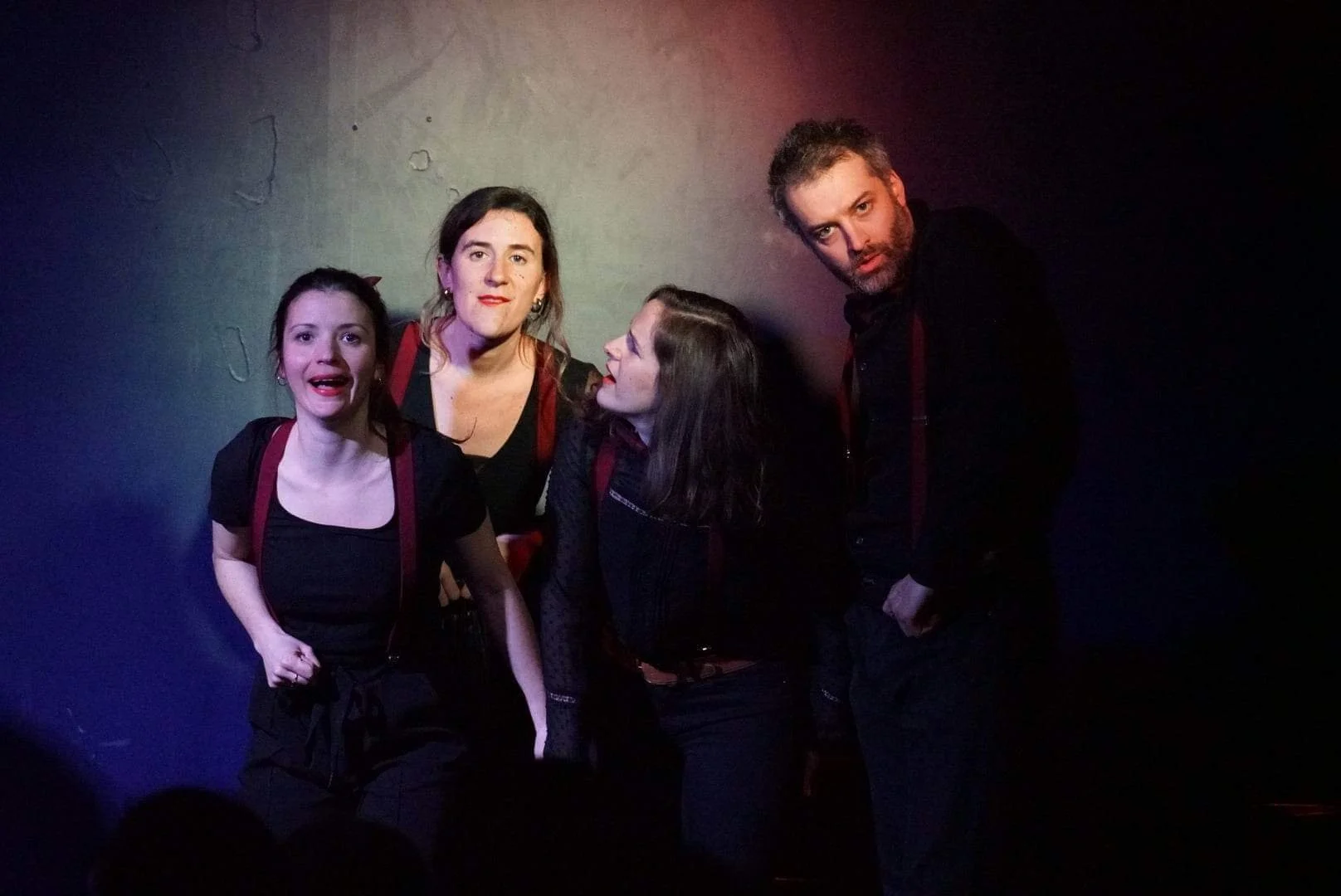 Quatre personnes posant ensemble dans un environnement sombre avec des lumières colorées, deux femmes et deux hommes, semblant être lors d'un événement ou d'une performance.