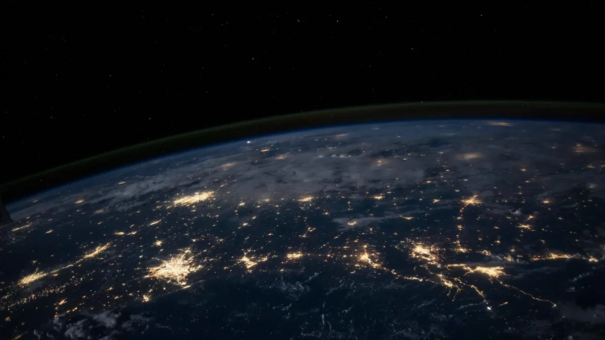 Earth from space at night showing city lights across continents — the 250+ destinations covered by Vegan Travel Guide