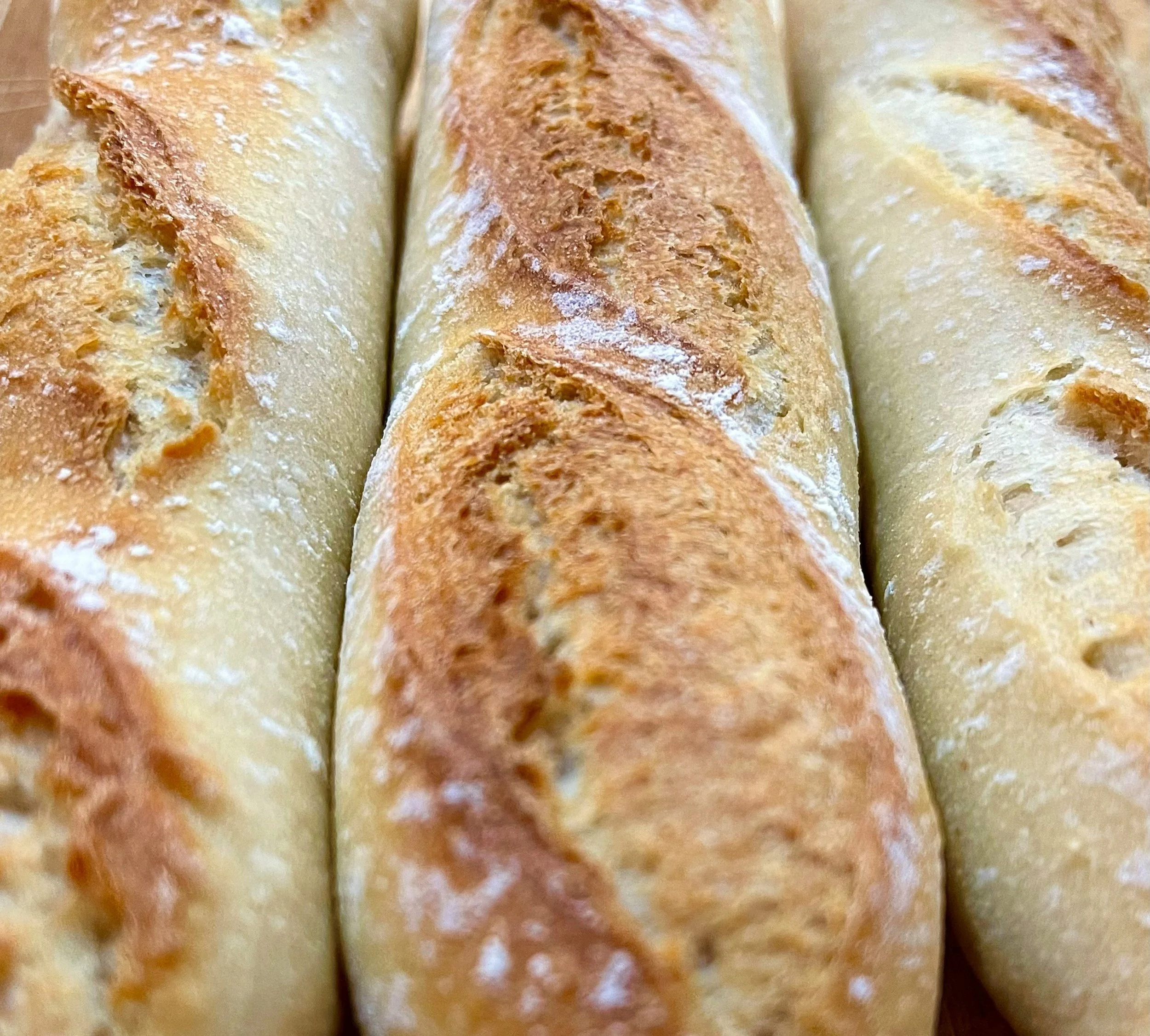 Close-up of three freshly baked baguette loaves with golden-brown crusts.