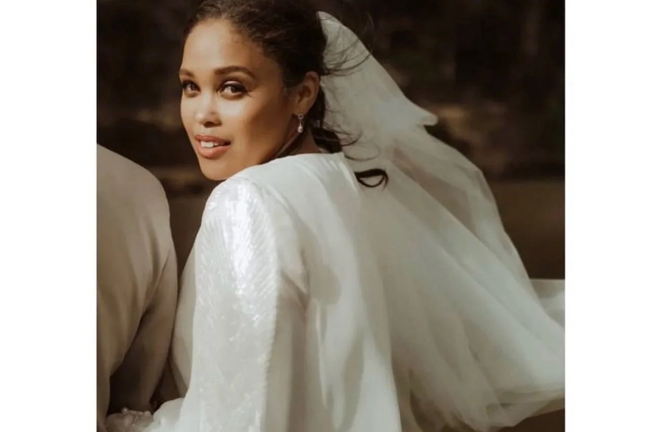 A bride with a white wedding gown and veil, smiling and looking over her shoulder. Makeup by Andrea van Den Houten based in Paris working globally 