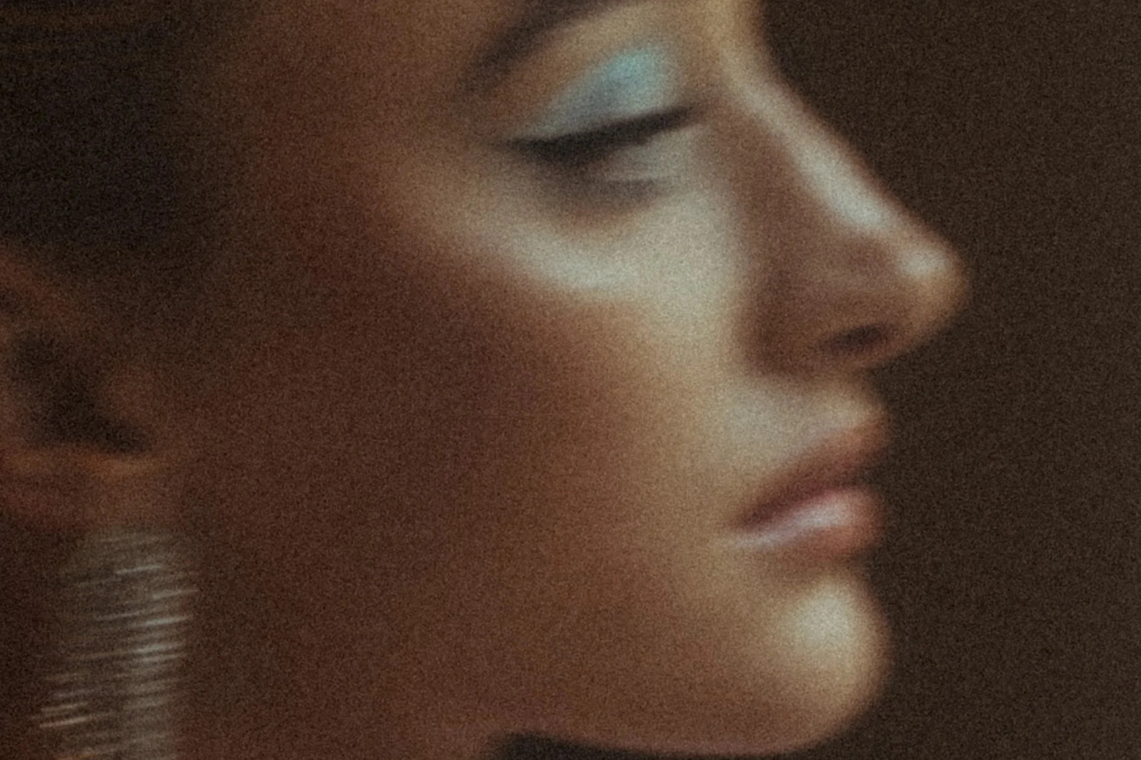 Close-up of a person's face with makeup, showing closed eyes with white eyeshadow, black eyeliner, and a hoop earring.Makeup by Andrea van Den Houten, based in Paris shot in Cape Town