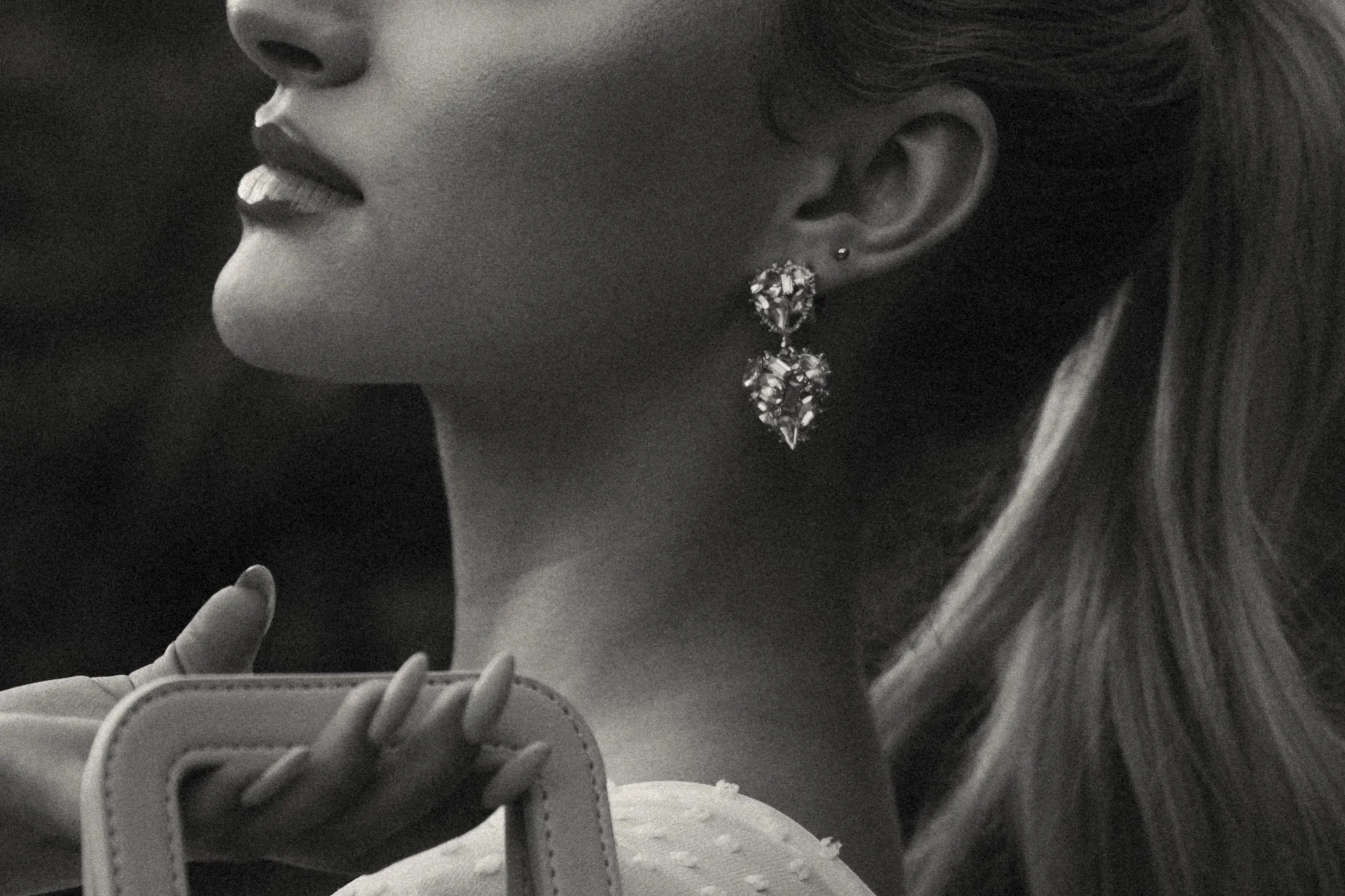 Close-up of a woman’s face in black and white, showing her lips, ear with earrings, and part of her hair and shoulder.