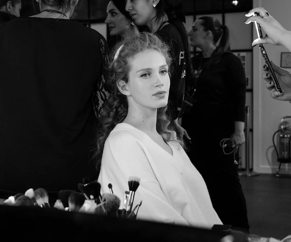 Candid behind-the-scenes fashion photography of a model backstage during a live fashion event