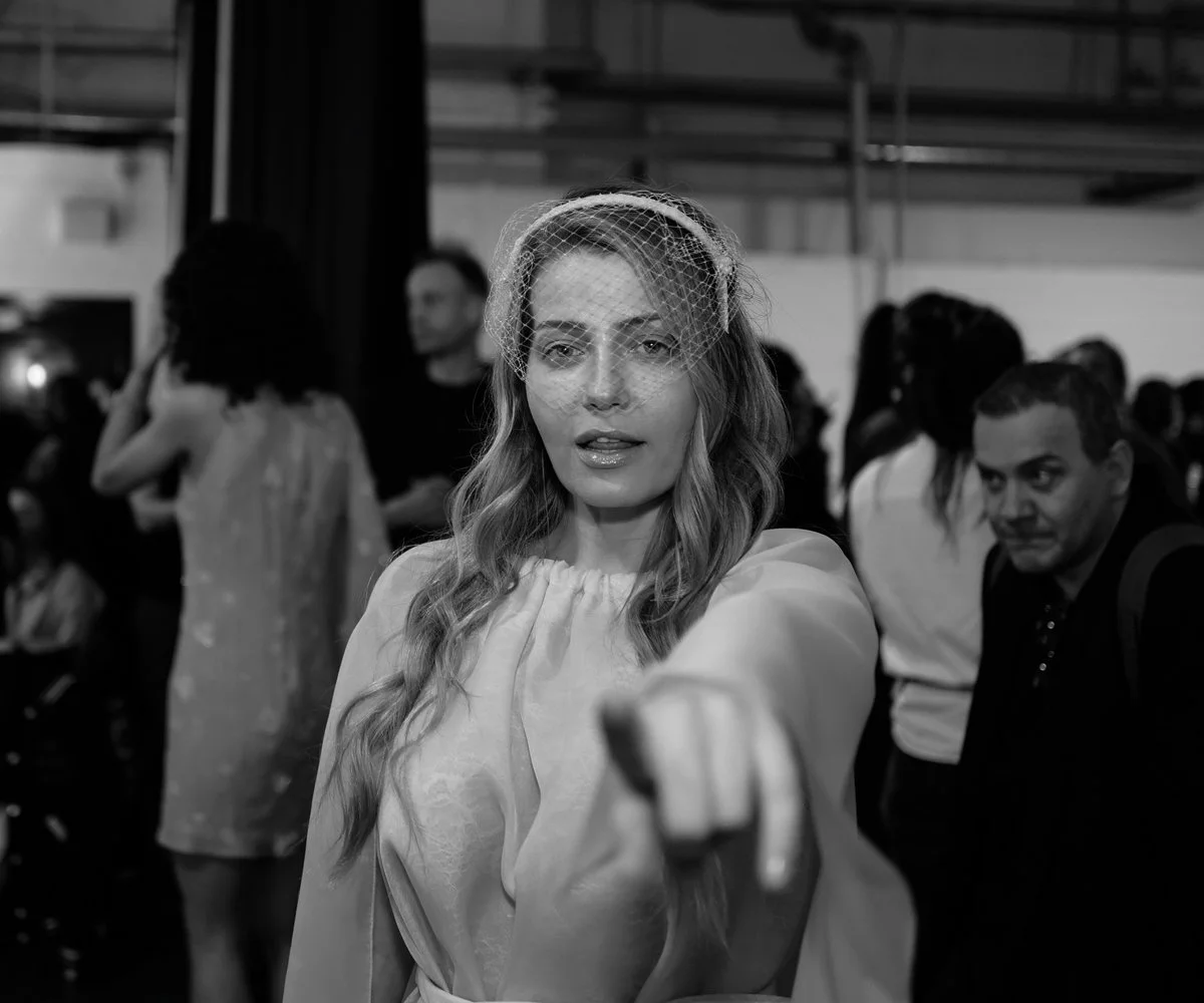 Behind-the-scenes fashion photography of a designer preparing garments backstage before a show