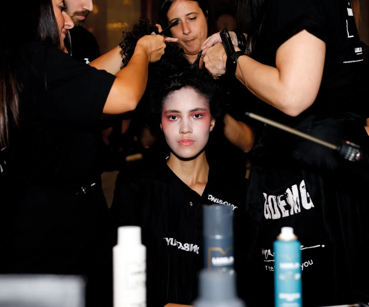 Backstage fashion photography capturing a candid moment between models and stylists during fashion week
