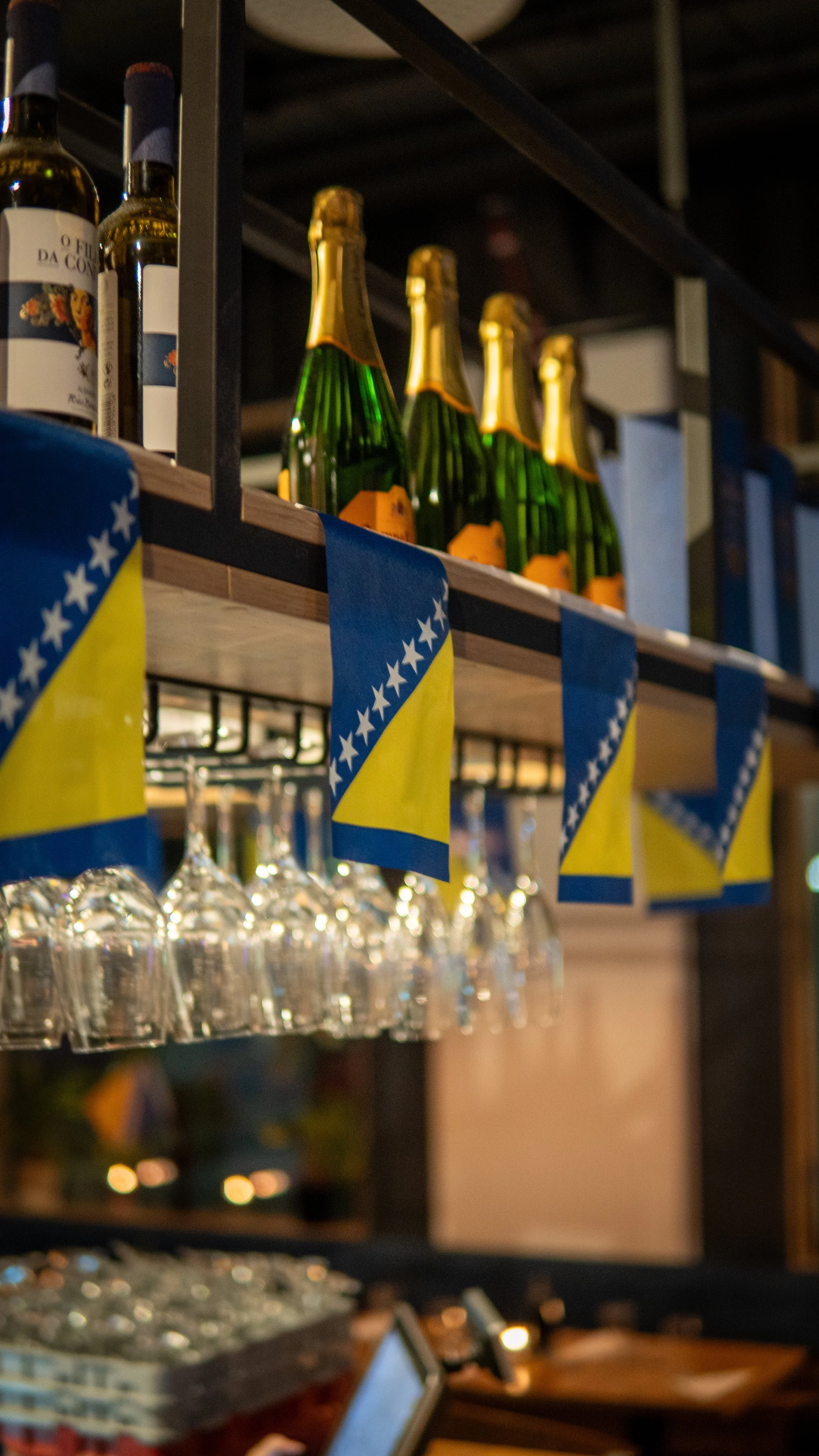 Bärbara flaskor champagne på hylla med flaggor av Bosnien och Hercegovina.