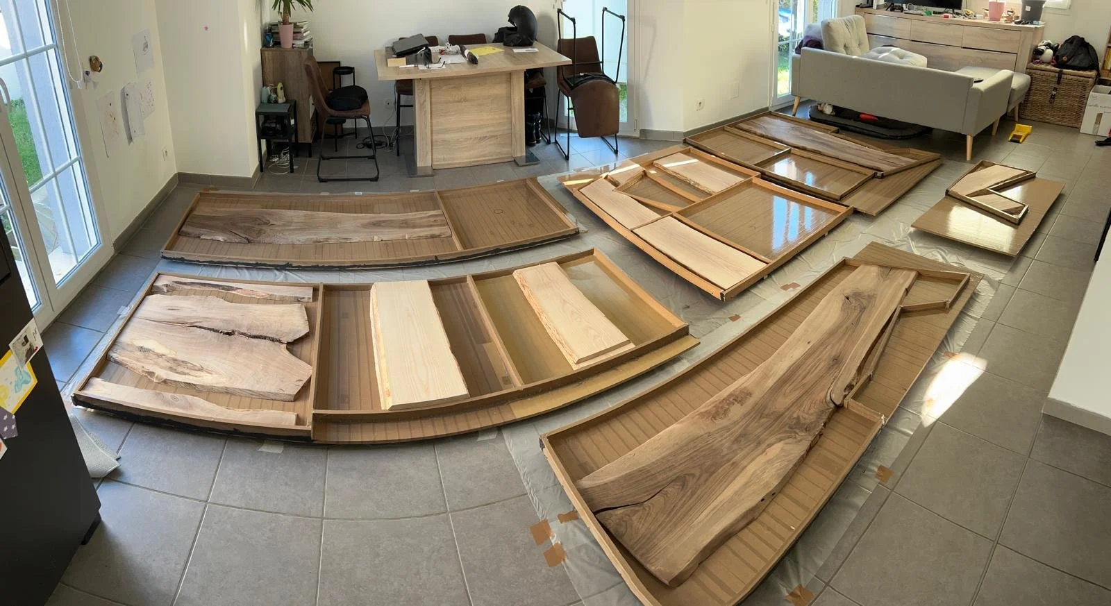 des plans en bois massif de différentes formes et tailles disposés sur le sol, prêt pour l'assemblage ou la fabrication.