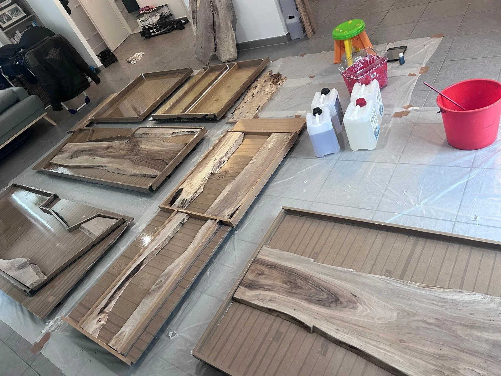 Table recouverte de pièces de bois naturelles et de cadres en bois, des bouteilles de résine, et des outils pour la résine