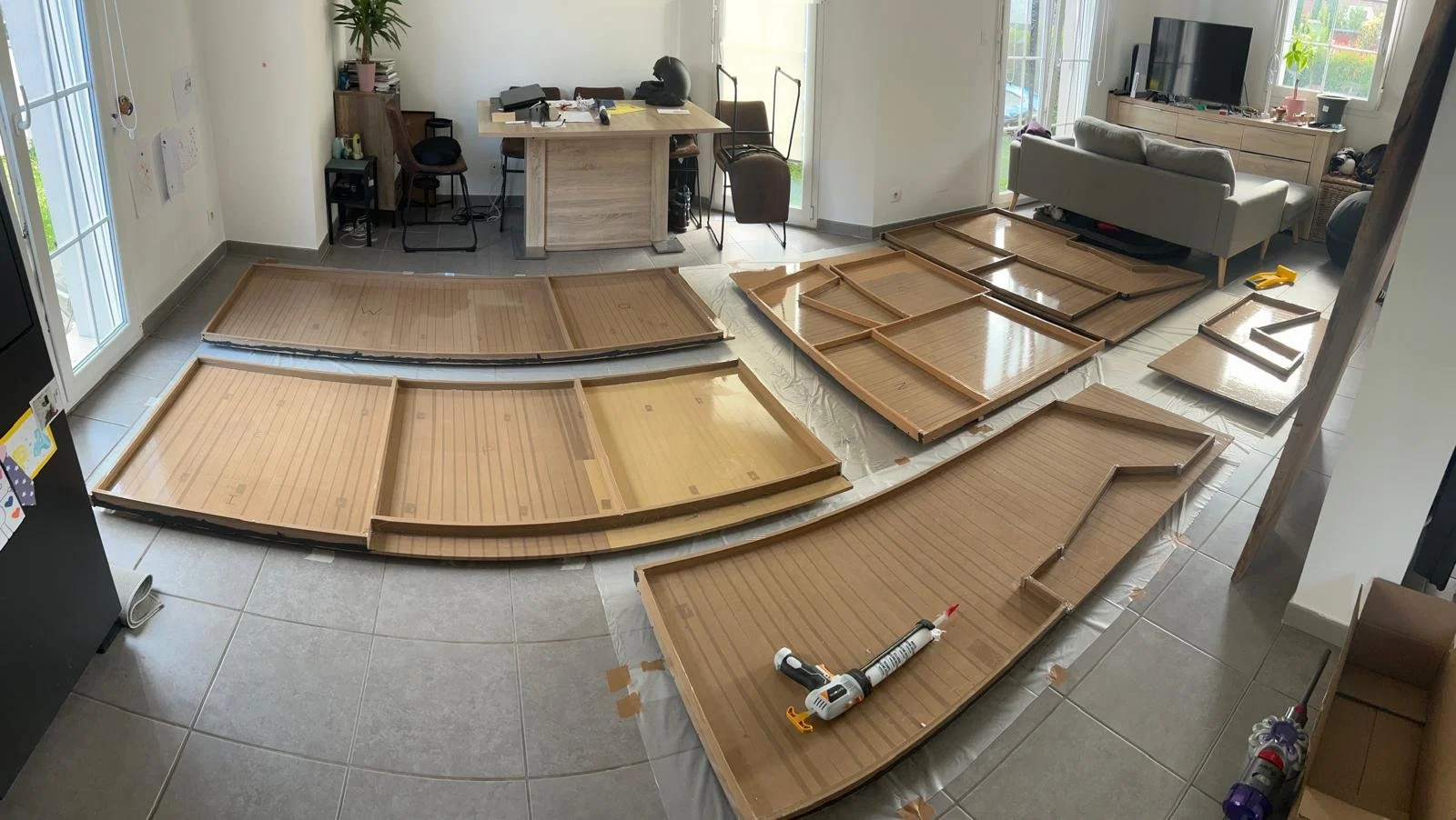 une grande surface recouverte de planches en bois en cours de montage, des outils posés sur le sol.