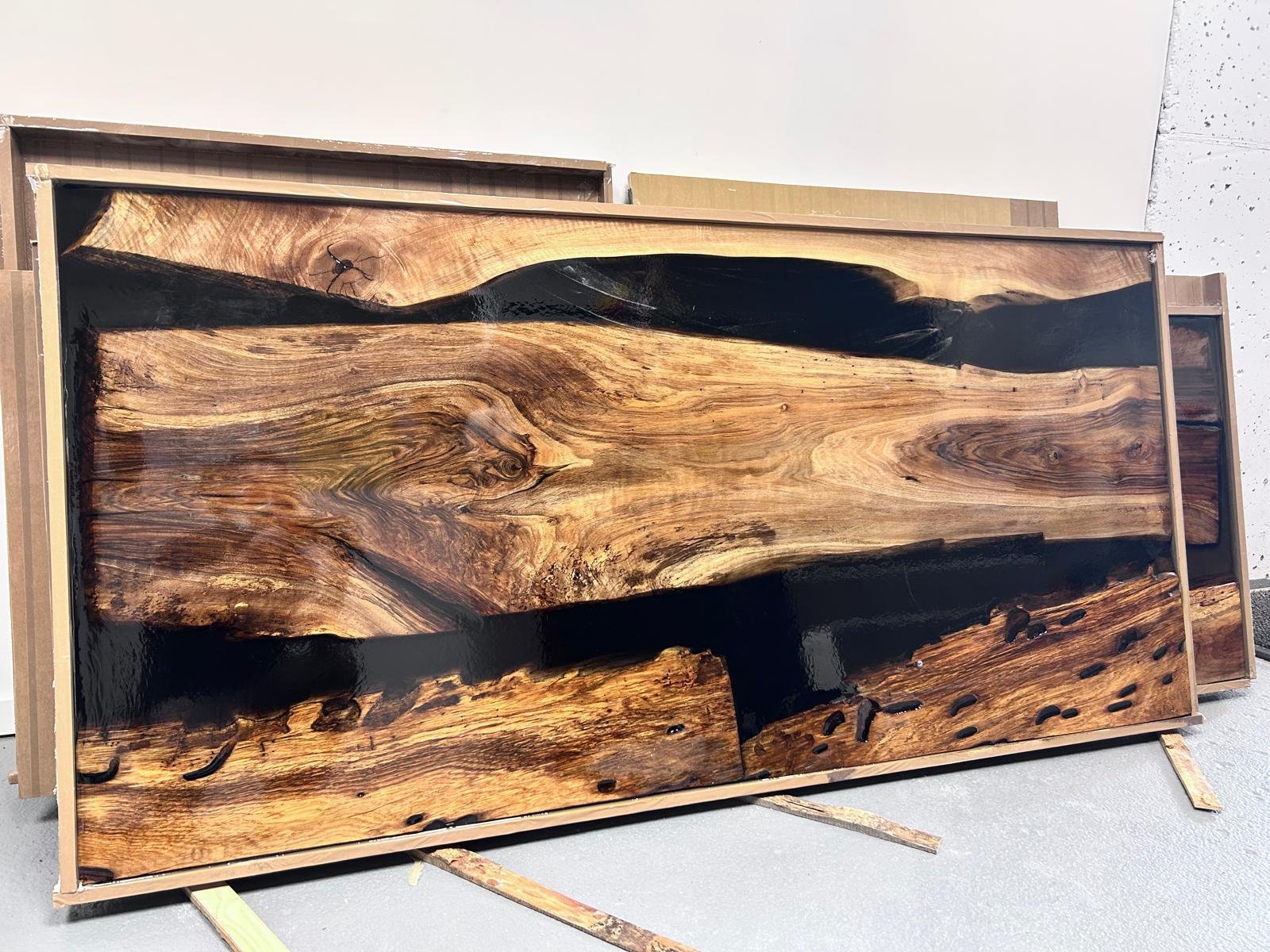 Table en bois avec finition brillante et motifs naturels, positionnée en intérieur sur un sol gris.