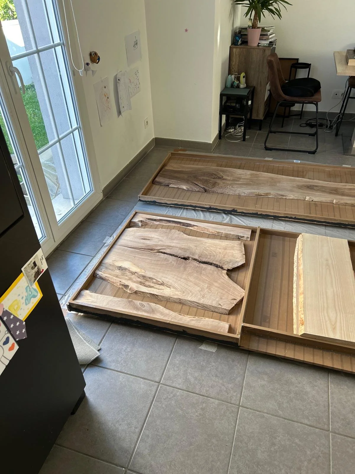 Plaques en bois brut disposées dans des cadres en bois sur un sol carrelé