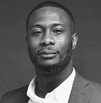 Black man in a suit and white shirt, looking at the camera with a neutral expression.