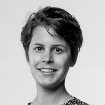 A black and white headshot of a young woman with short, wavy hair, smiling at the camera.