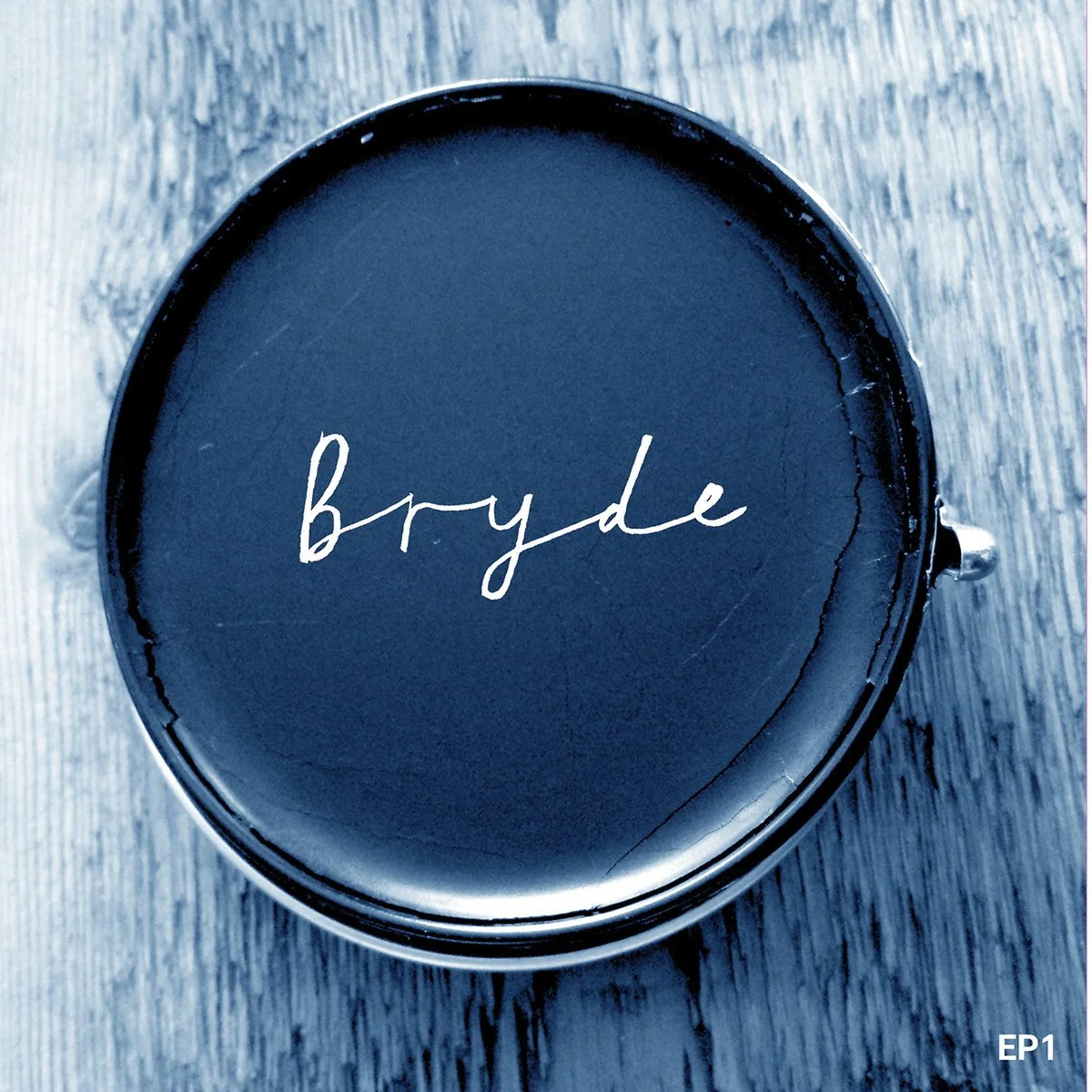 A cup of black coffee on a wooden surface with the name 'bryde' written on the surface of the coffee.