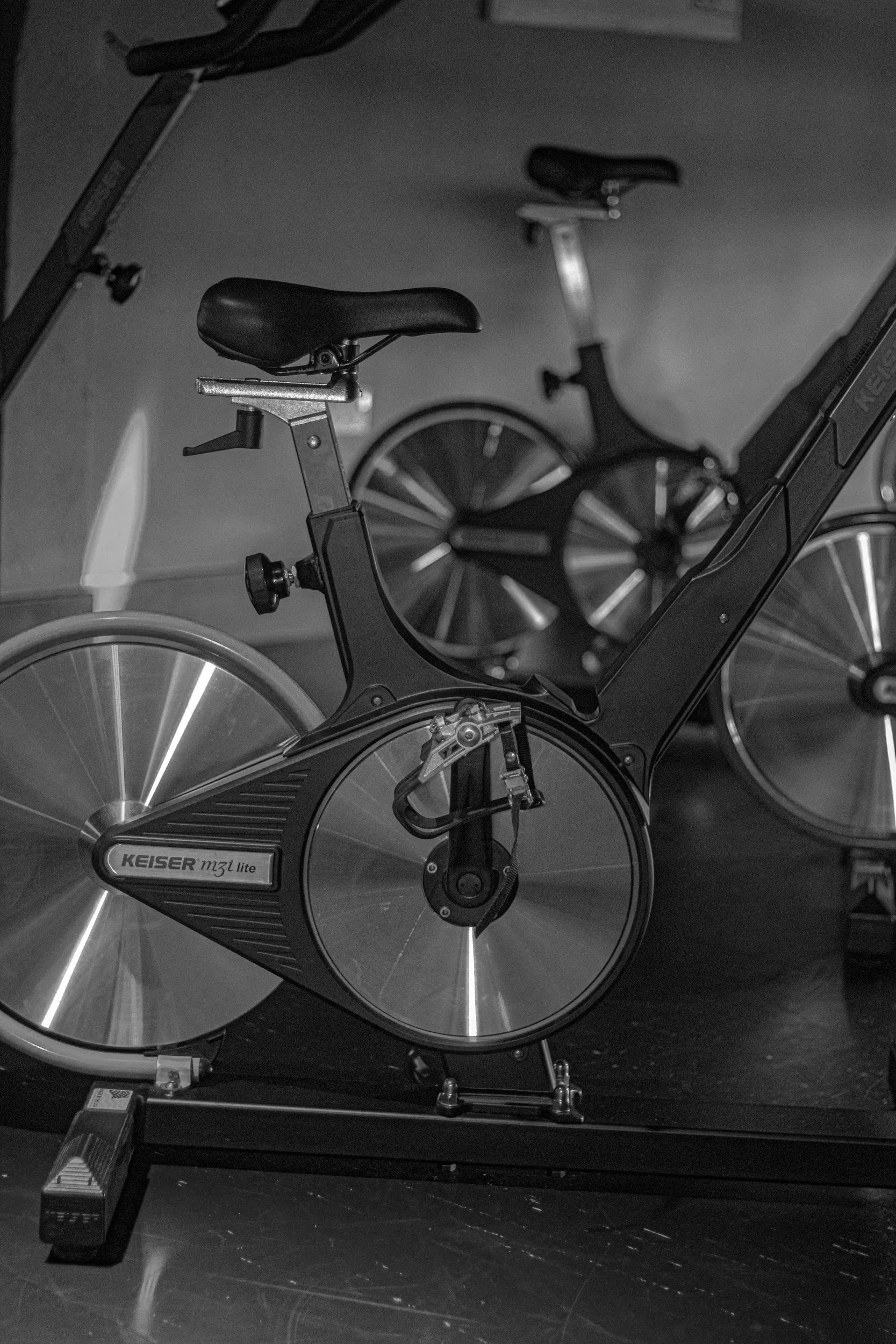 Black and silver Keiser M3i Lite stationary exercise bikes in a gym.