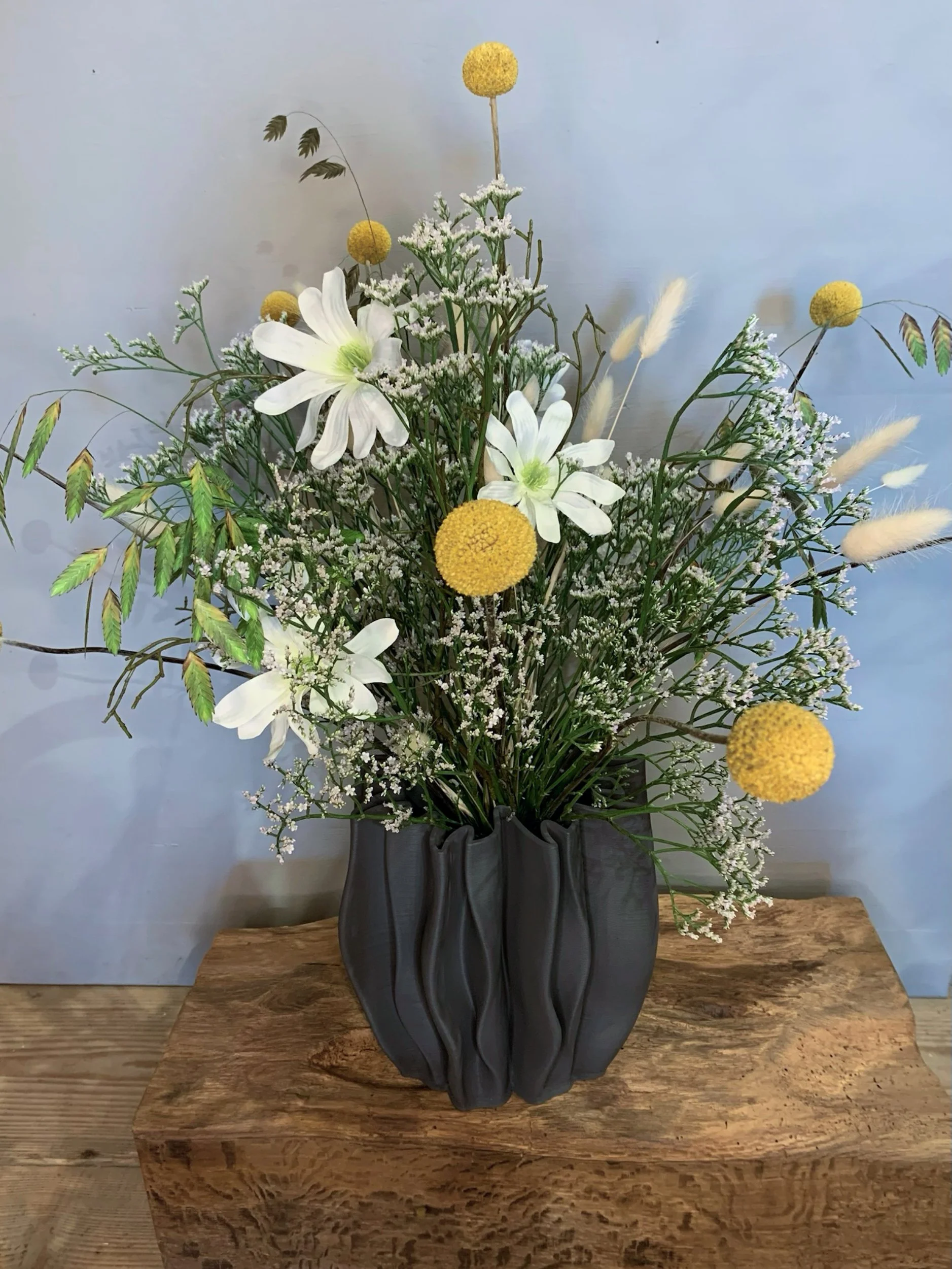 Blumenstrauß in einer schwarzen Vase auf einem Holzblock