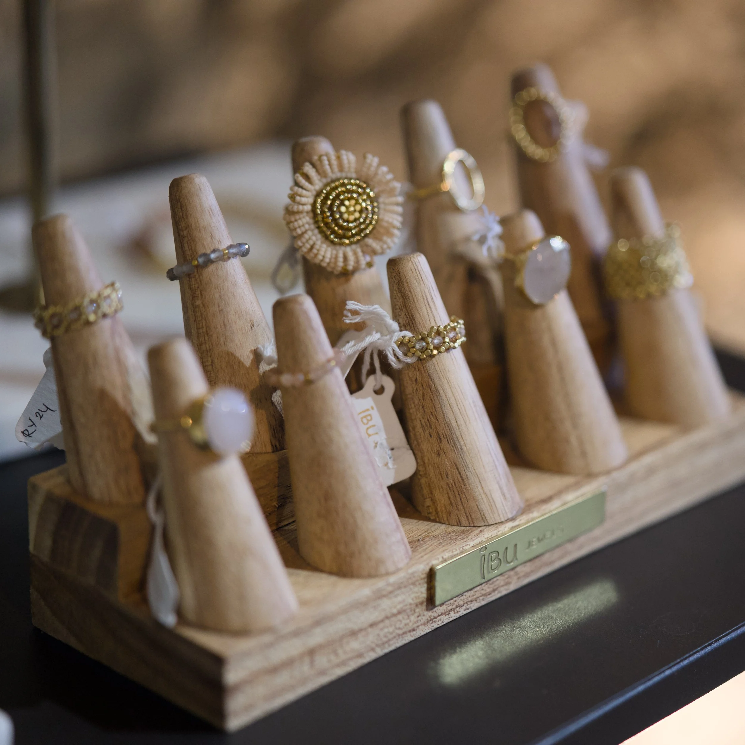 Nahaufnahme von mehreren Ringen auf kleinen Holzpüppchenständern, einige mit goldfarbenen Perlen und Schmuck.
