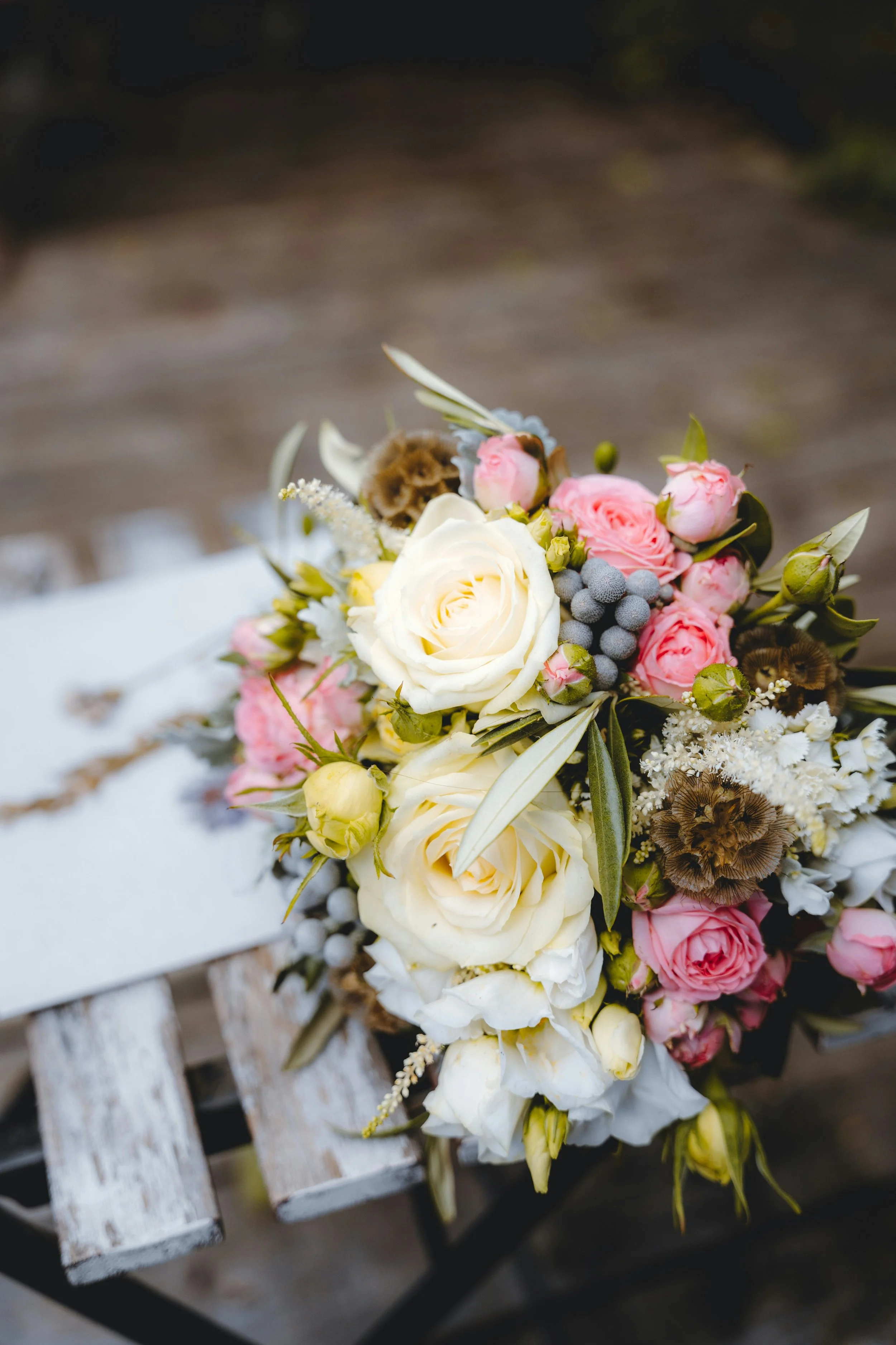 Blumenstrauß mit weißen und rosa Blumen, auf einer alten Holzbank