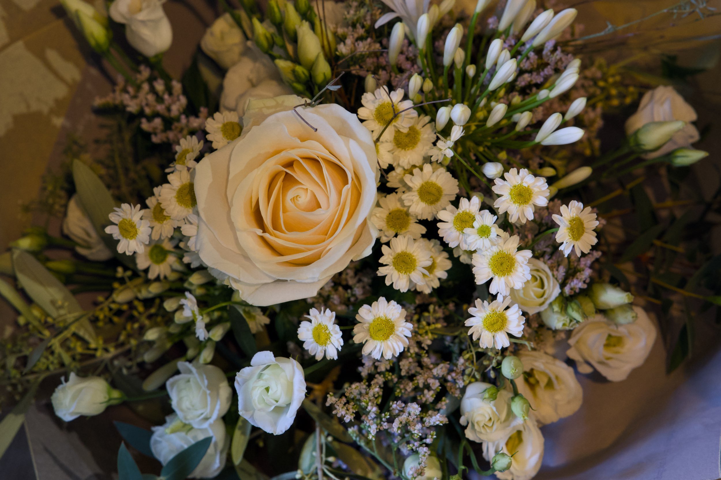 Blumenstrauß mit weißen Rosen, kleinen weißen Gänseblümchen und vielen weißen Blumen in einer Vase.