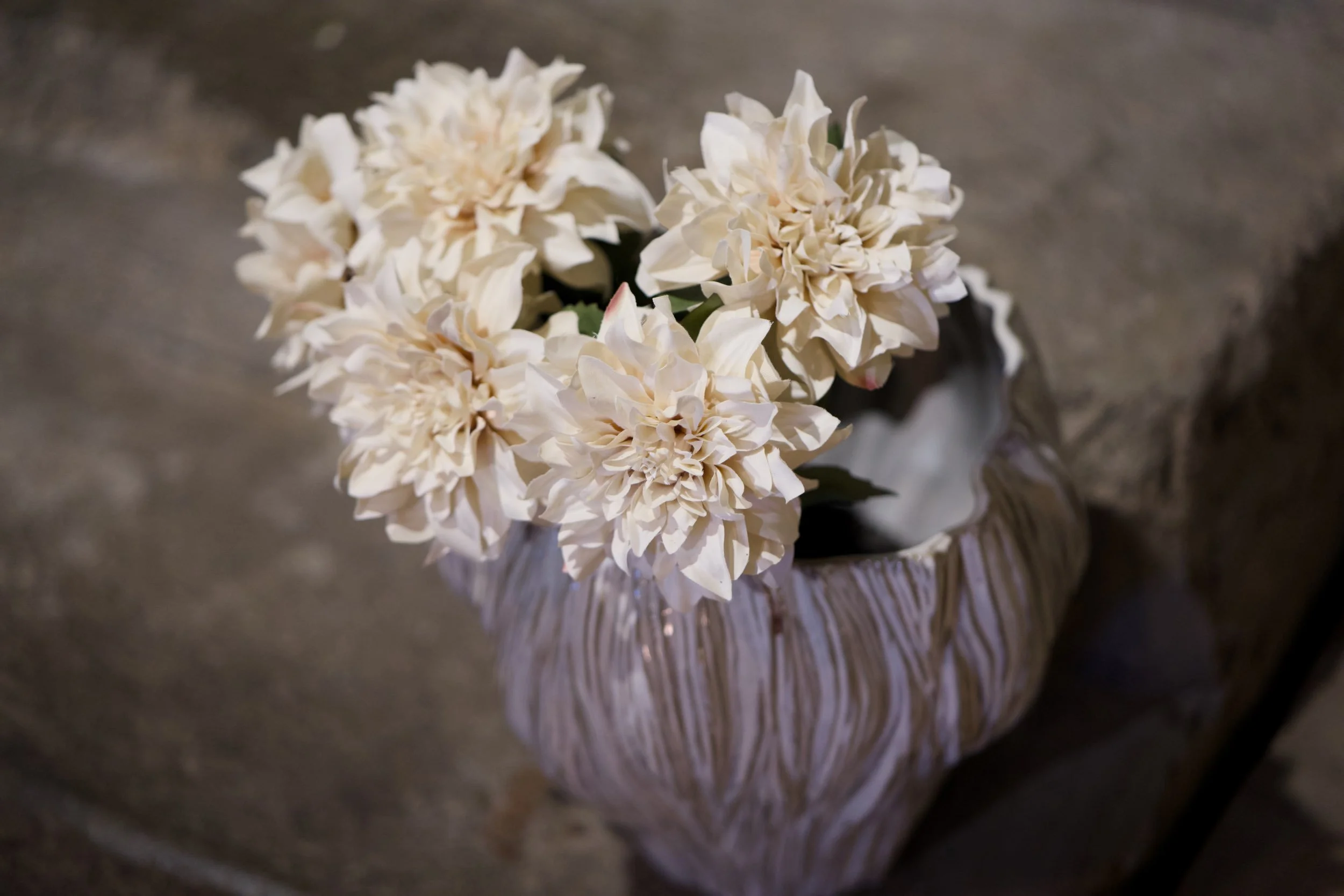 Weiße Blüten in einer Vase auf einem Tisch.