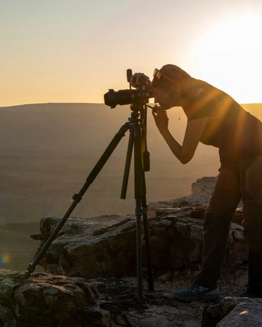 Fotografo che scatta una foto in un paesaggio desertico al tramonto.