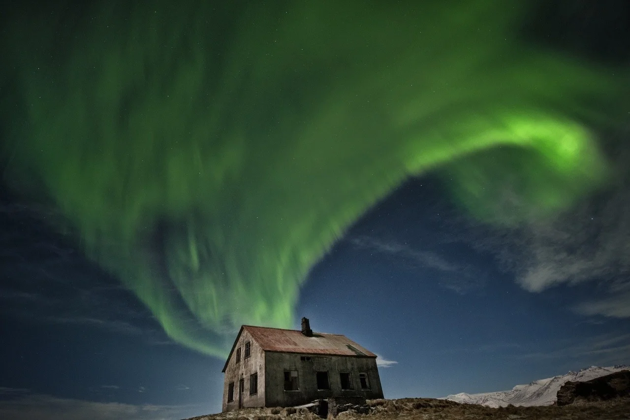 Casa abbandonata sotto le luci dell'aurora boreale nel cielo notturno