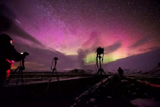 Fotografi di astronome che scattano foto dell'aurora boreale e del cielo stellato notturno