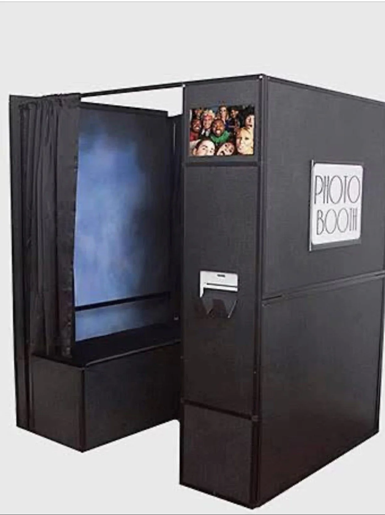 A black photo booth with a sign that says 'Photo Booth' on the side. It has a small screen at the top showing cartoon faces and an open area with a curtain for taking pictures.