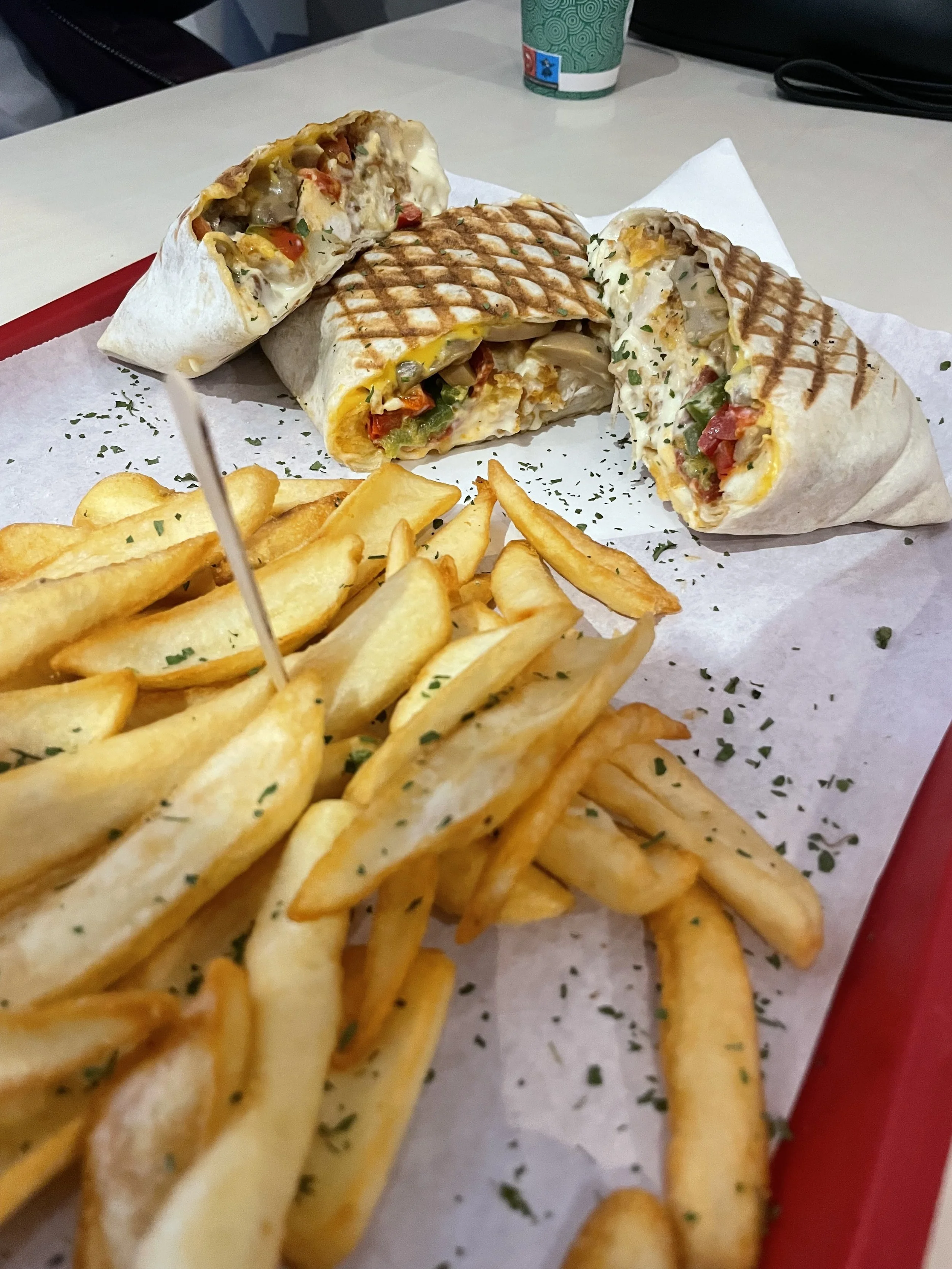 Sandwichs rollés coupés en deux avec des légumes, accompagnés de frites, sur une plaque avec du persil haché. Tacos O'bread à Rennes
