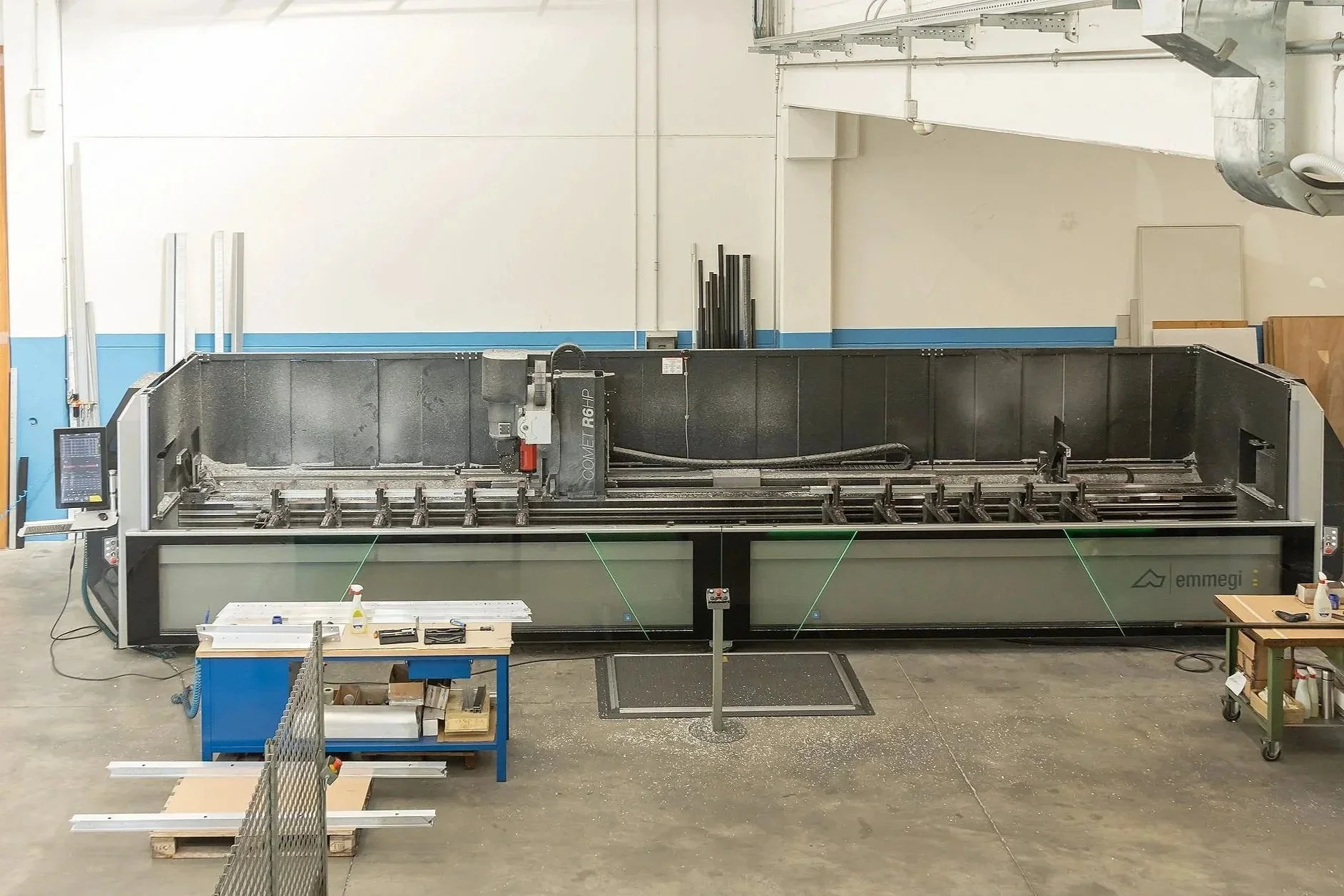 Macchina laser di grandi dimensioni in un’officina, con vari strumenti e una postazione di lavoro accanto.