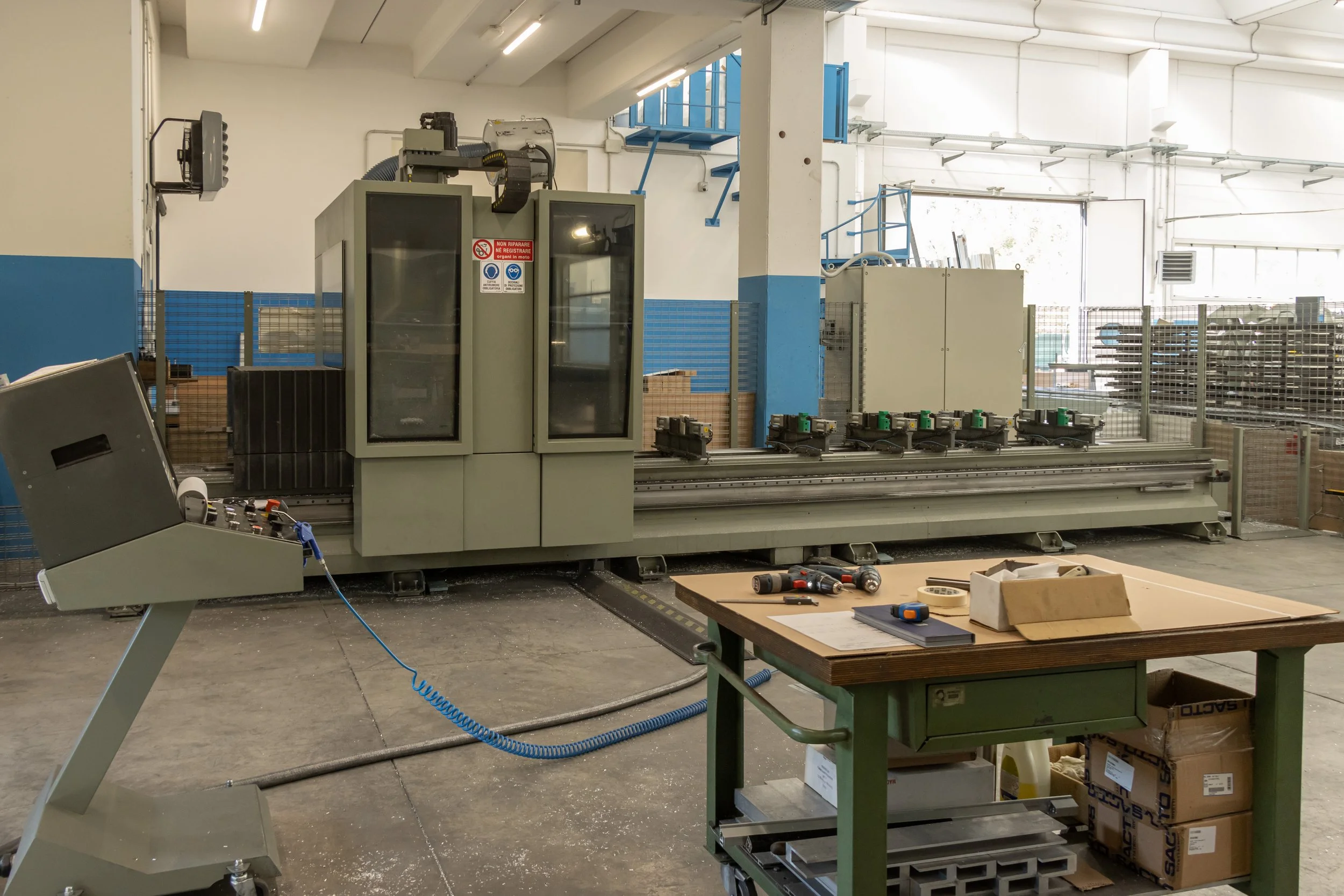 Macchina industriale in un officina, con strumenti e materiale sul banco di lavoro davanti