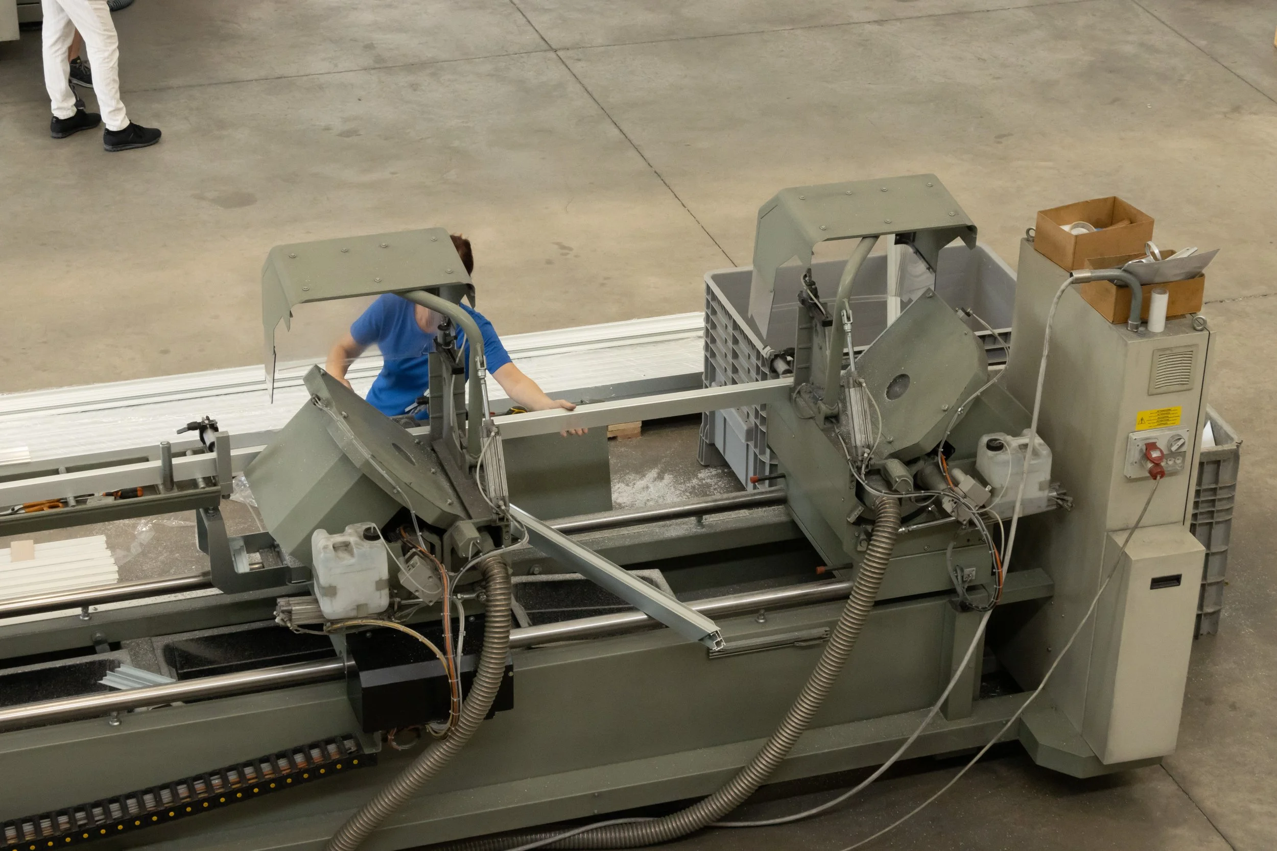 Foto di una macchina industriale in un magazzino con alcune persone che lavorano vicino.