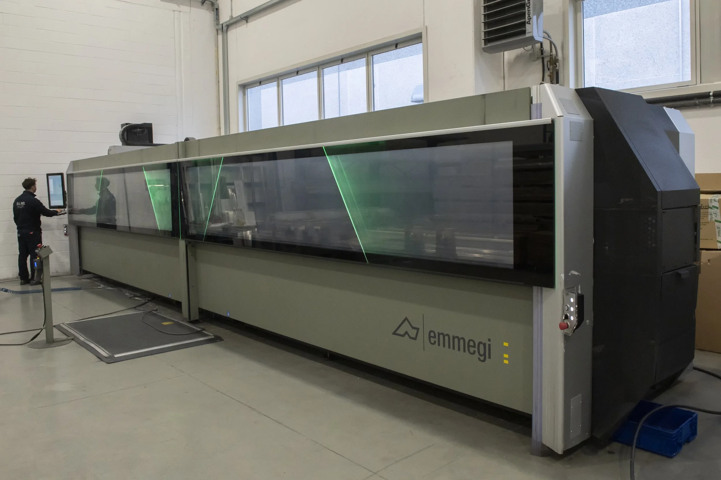 Macchina di controllo laser nello stabilimento industriale di Emmegi con operatore che usa un monitor.