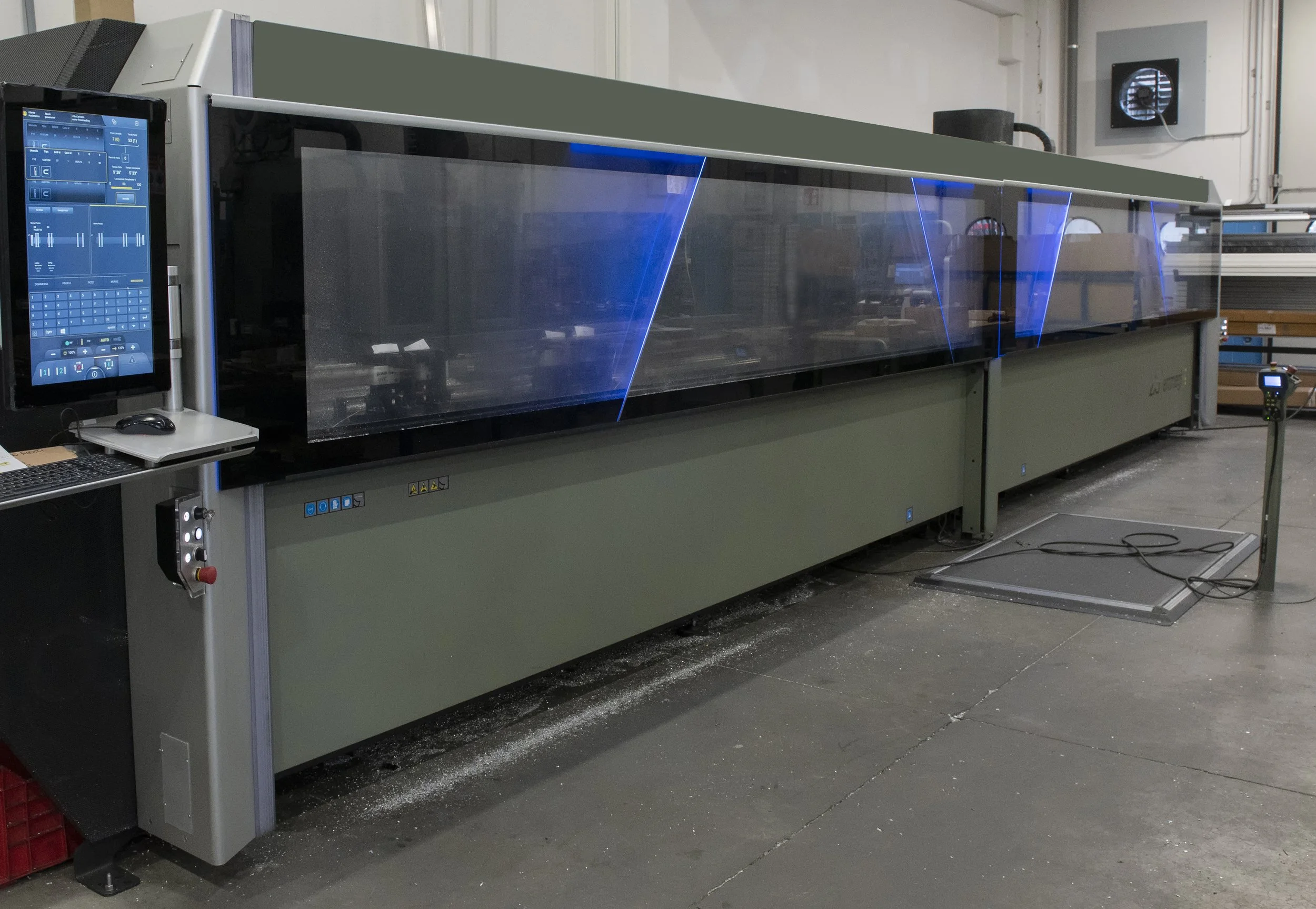 Grande macchina industriale con schermo touch e pannello di controllo, usata per lavorazioni di precisione in un ambiente di produzione.