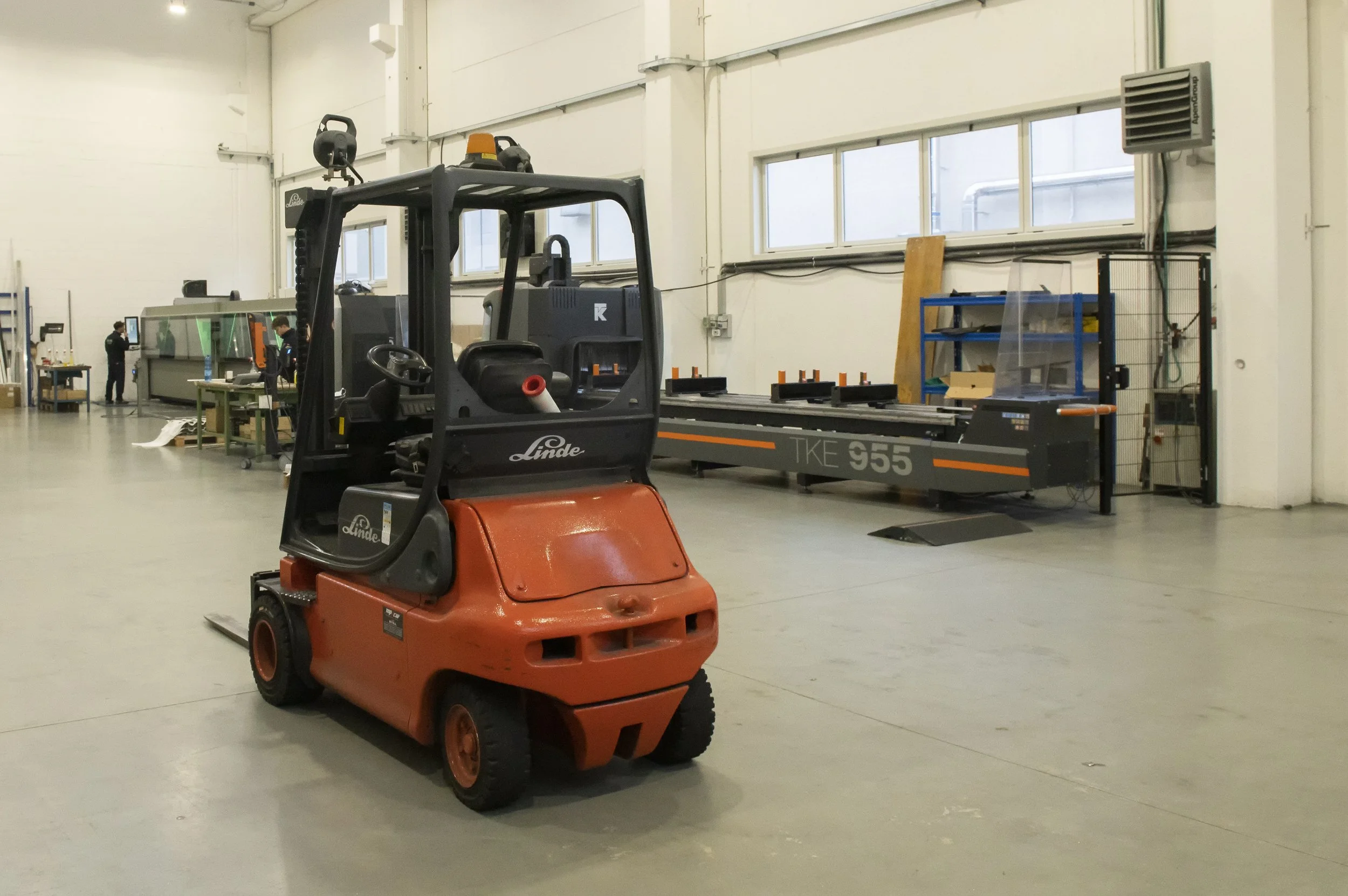 Carrello elevatore nel magazzino industriale con attrezzature e macchinari in background.