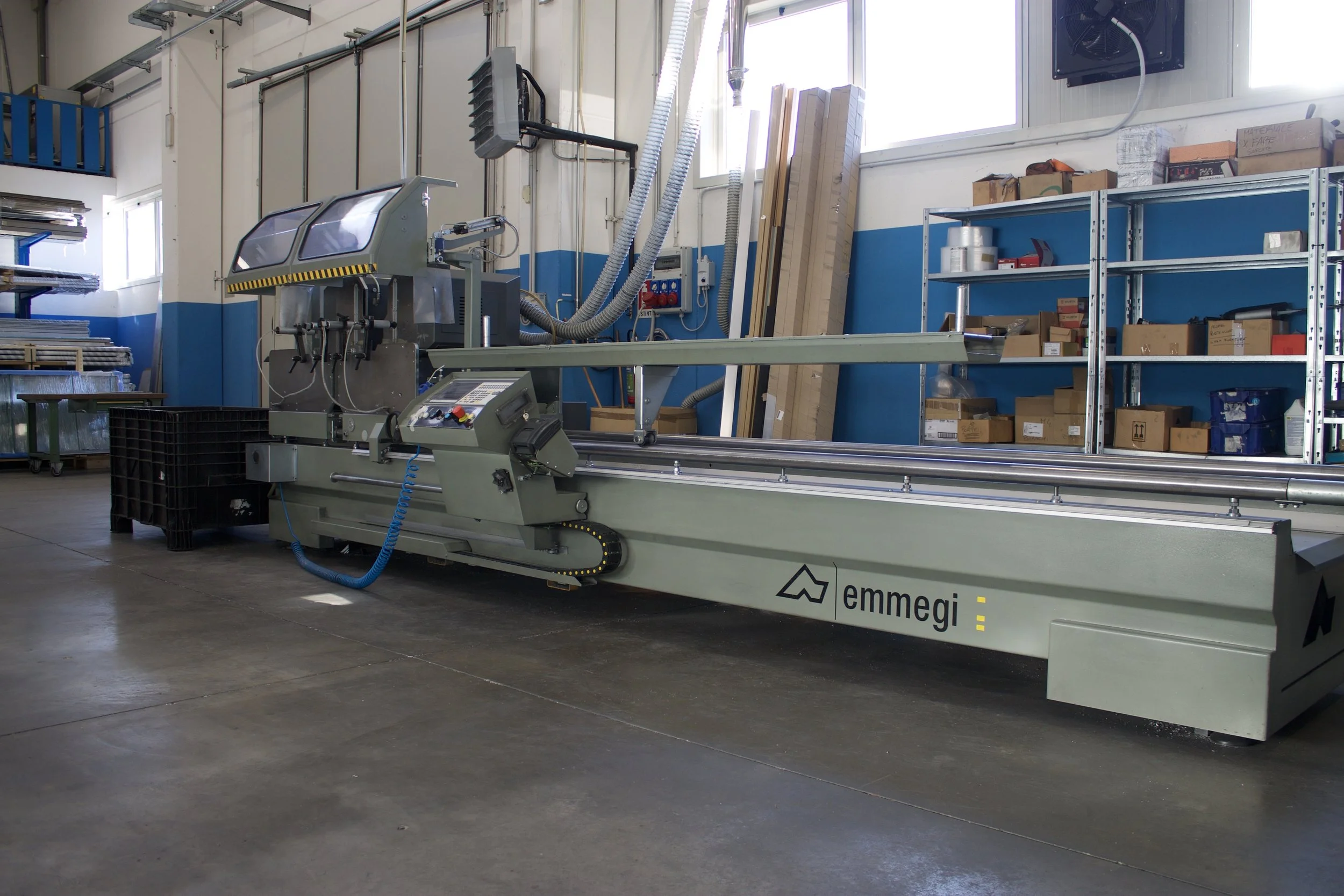 Macchina industriale in un'officina, marca Emmegi, usata per lavorare materiali come alluminio o plastica.