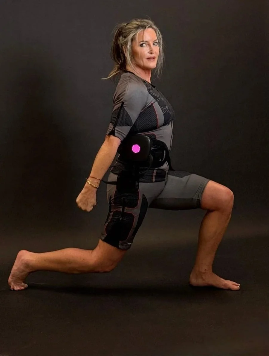 Woman in athletic wear in a lunge pose against a black background, with a wearable device on her arm.