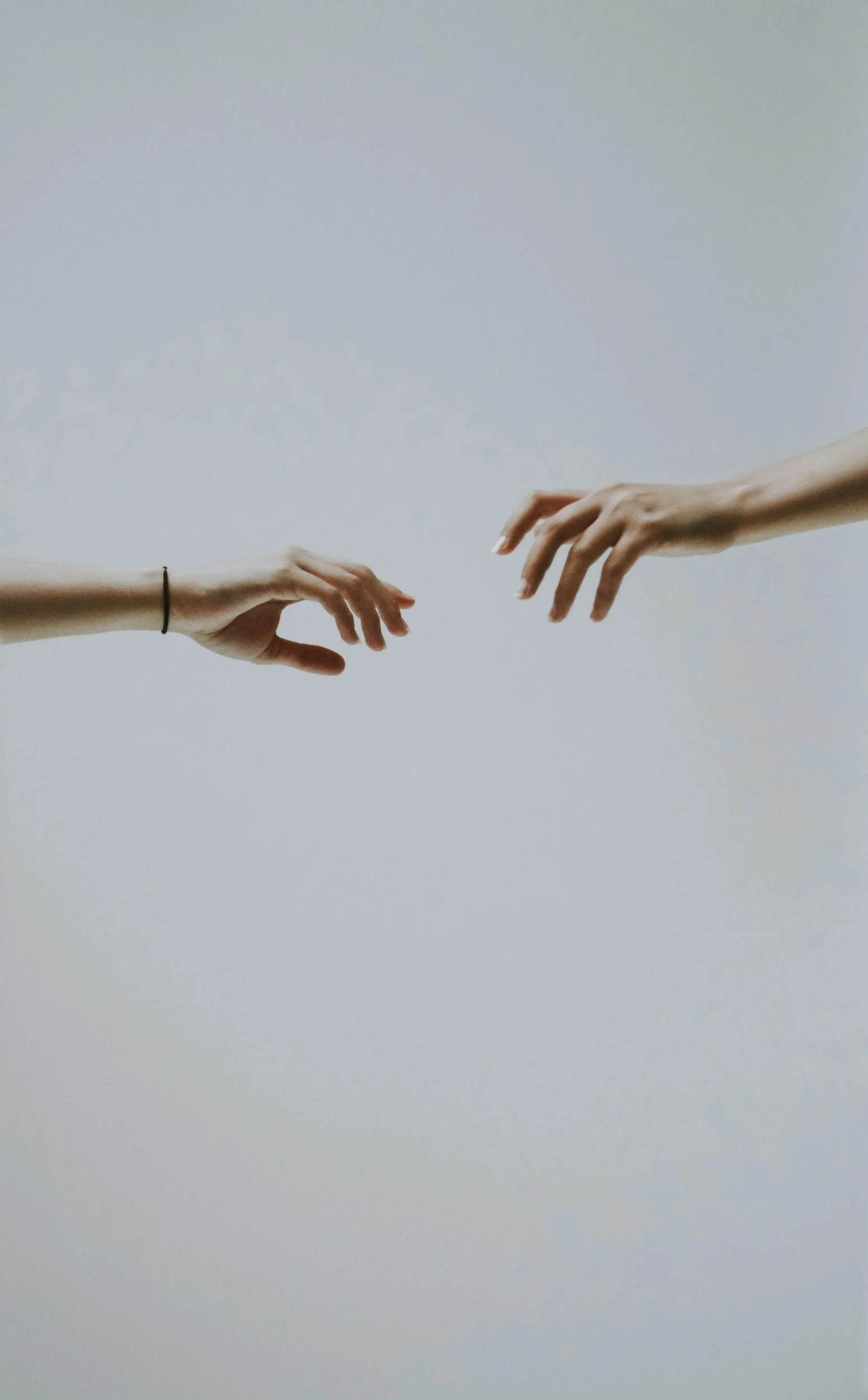 Two hands reaching toward each other against a plain background, reminiscent of the 'Creation of Adam' painting.