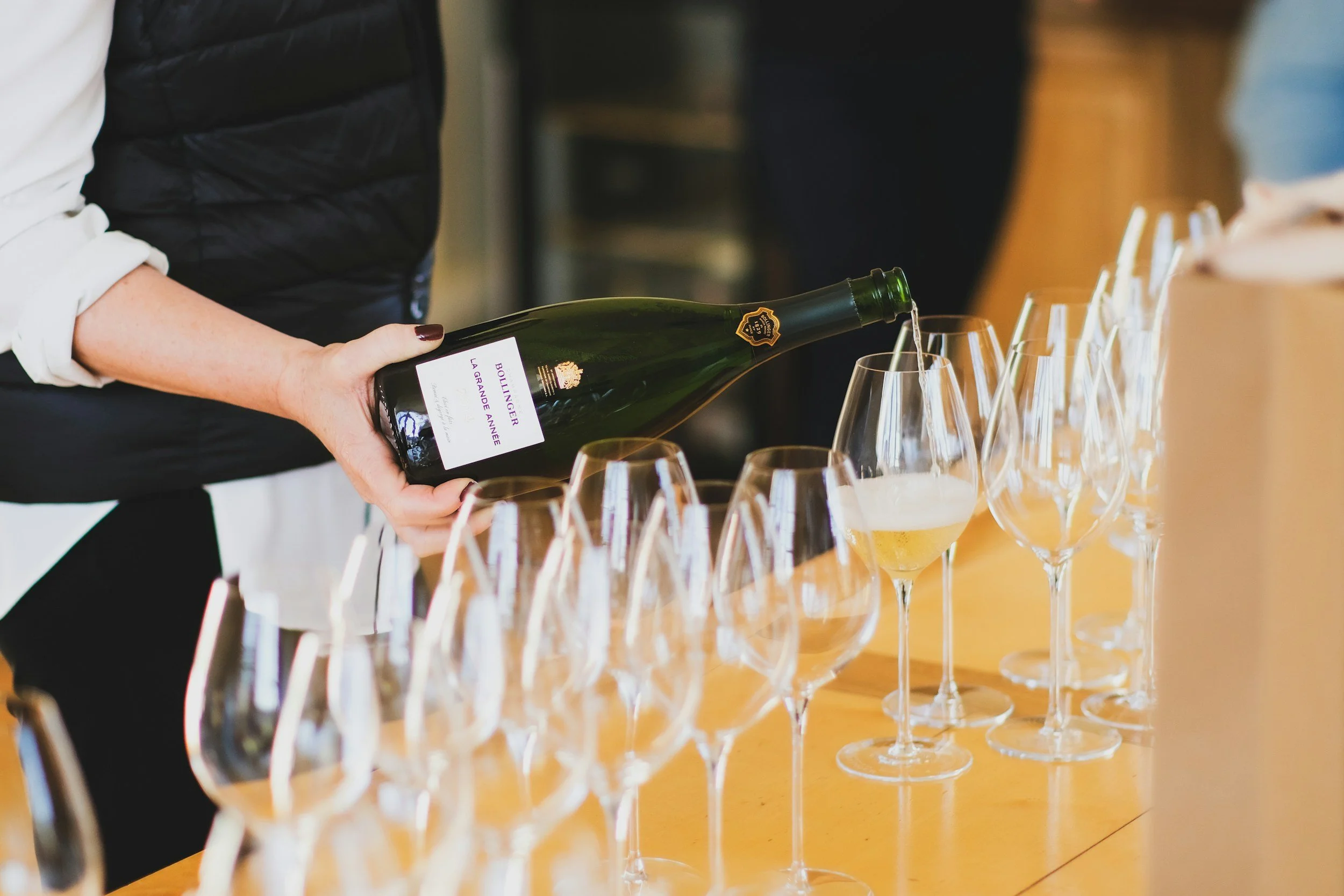 Person pouring champagne into glasses at a tasting event.